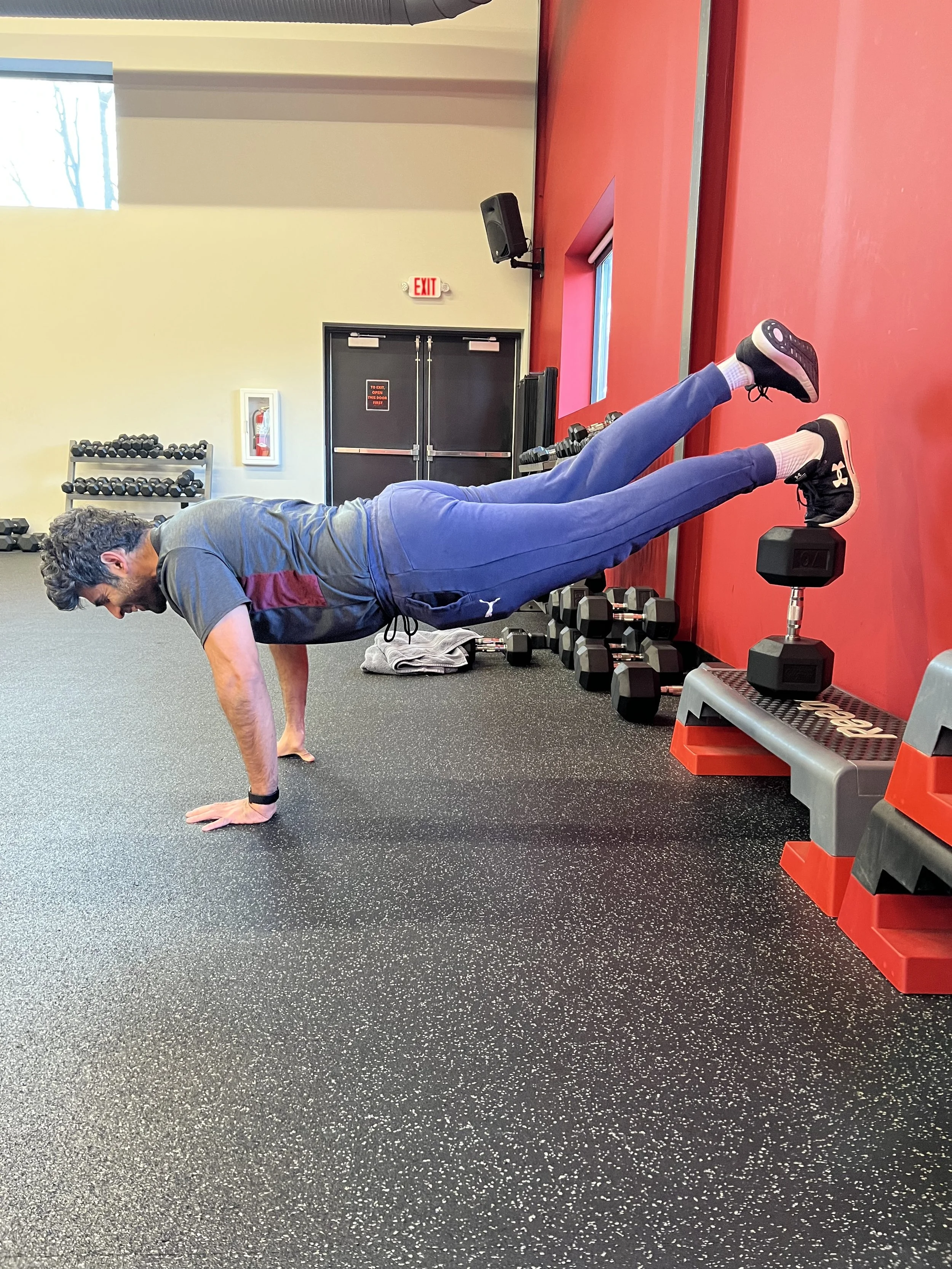 An Athlete Instincts member performing an elevated push-up with feet balanced on weights, demonstrating advanced fitness skills.