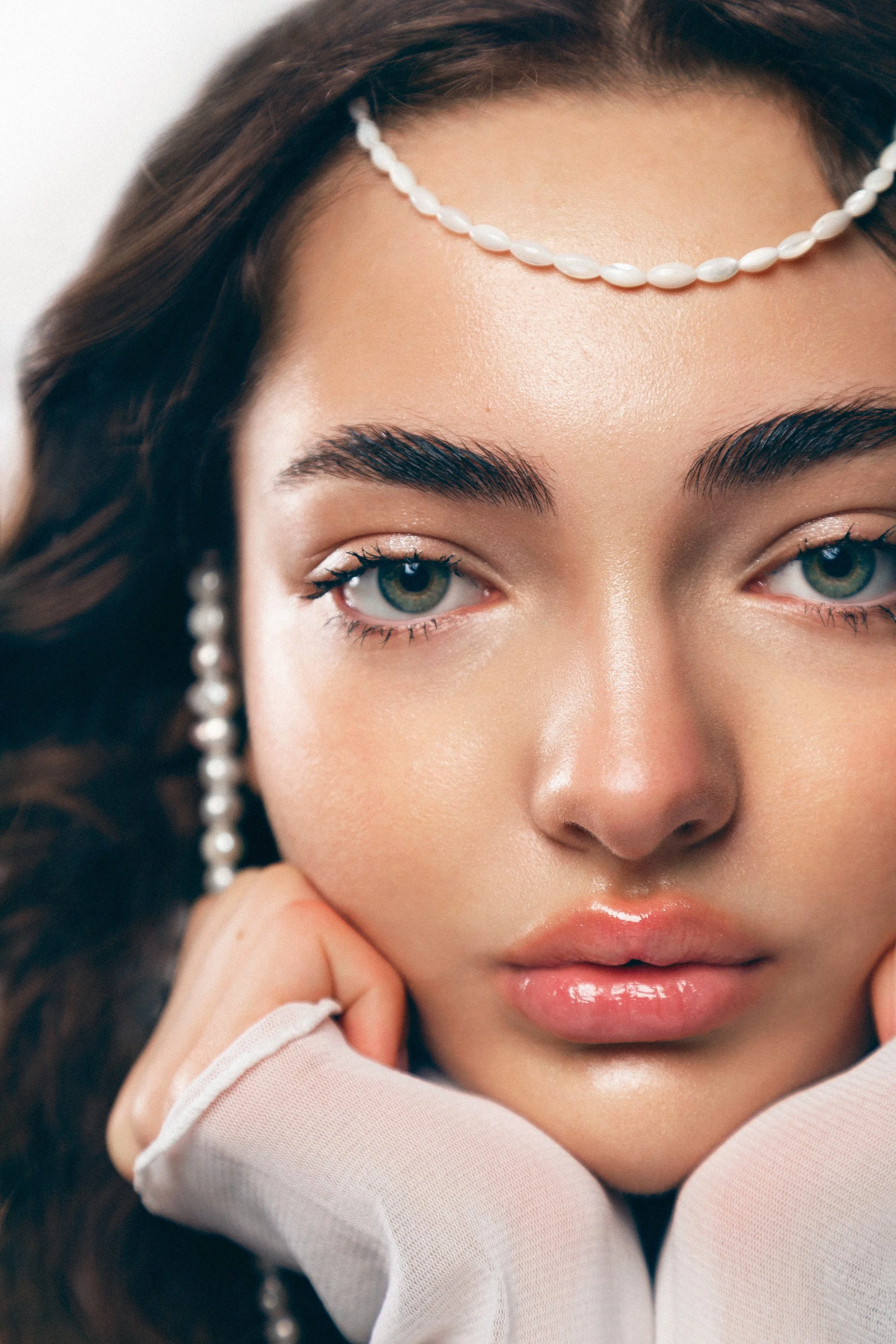 Shooting beauté dans un studio parisien avec la photographe Charlène Grimaud, mettant en avant un look sophistiqué. La coiffure, signée Maxime Guicheteau, crée un effet mouillé élégant