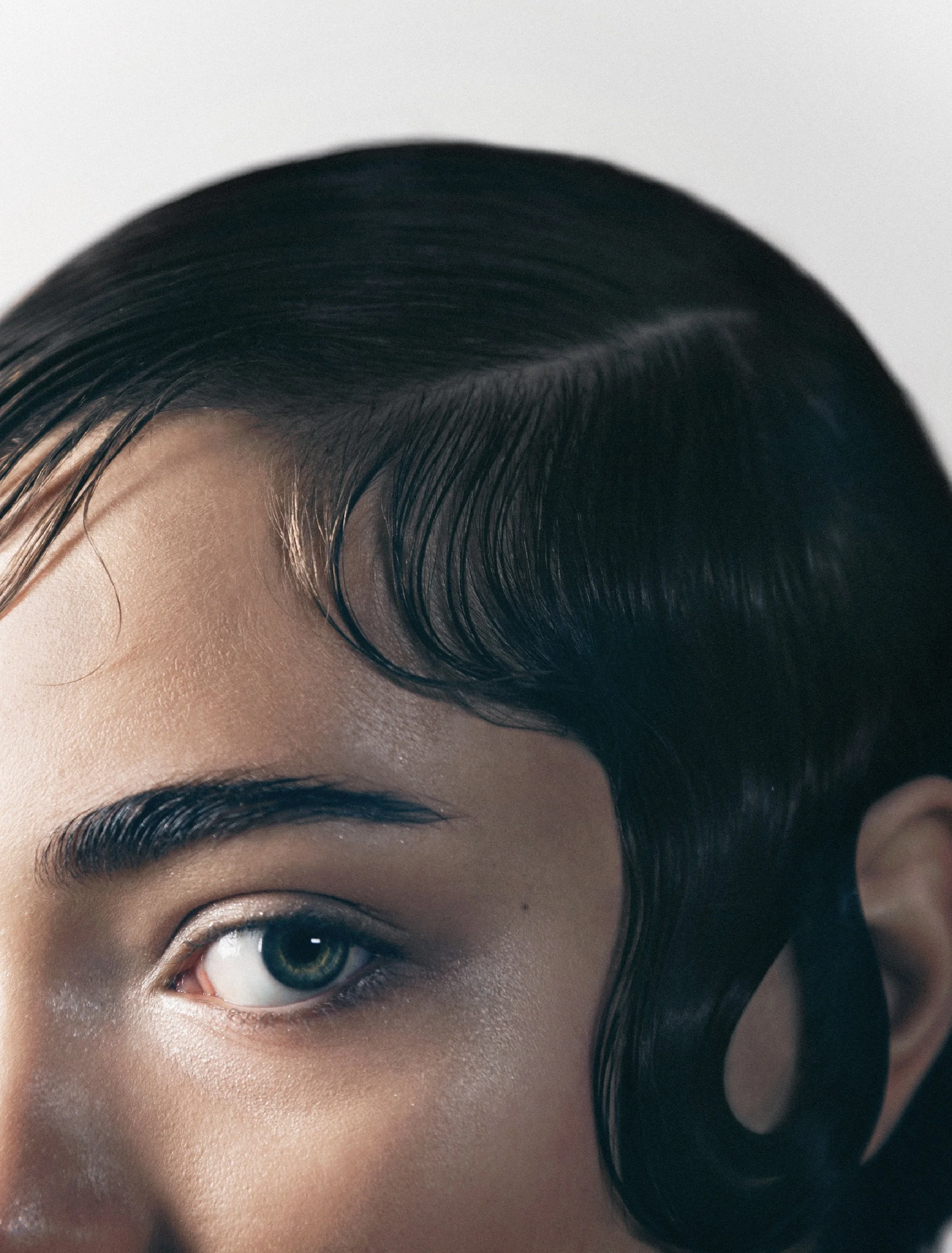 Shooting beauté dans un studio parisien avec la photographe Charlène Grimaud, mettant en avant un look sophistiqué. La coiffure, signée Maxime Guicheteau, crée un effet mouillé élégant