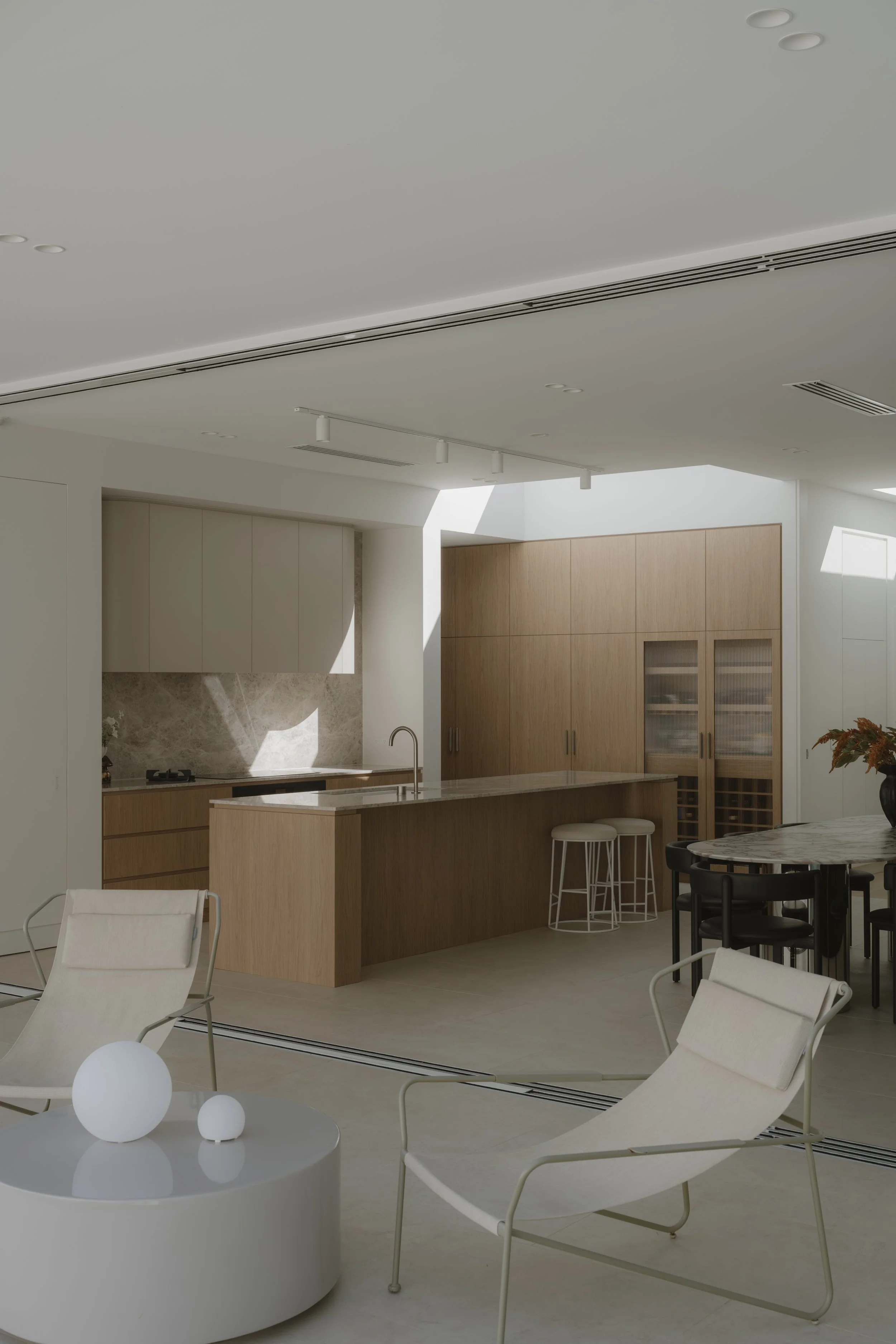 Modern kitchen and dining area with white and wood finishes, minimalist furniture, and natural light.