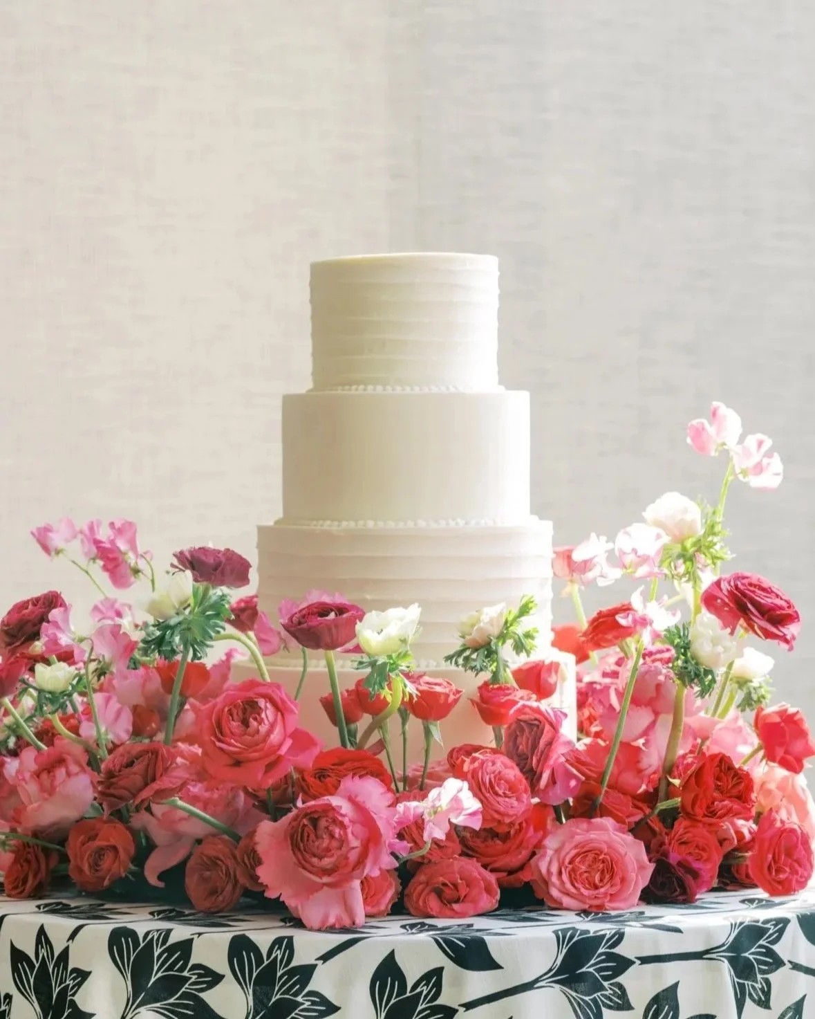 Three-tier wedding cake surrounded by a pink floral meadow of spring flowers at the Austin Proper Hotel