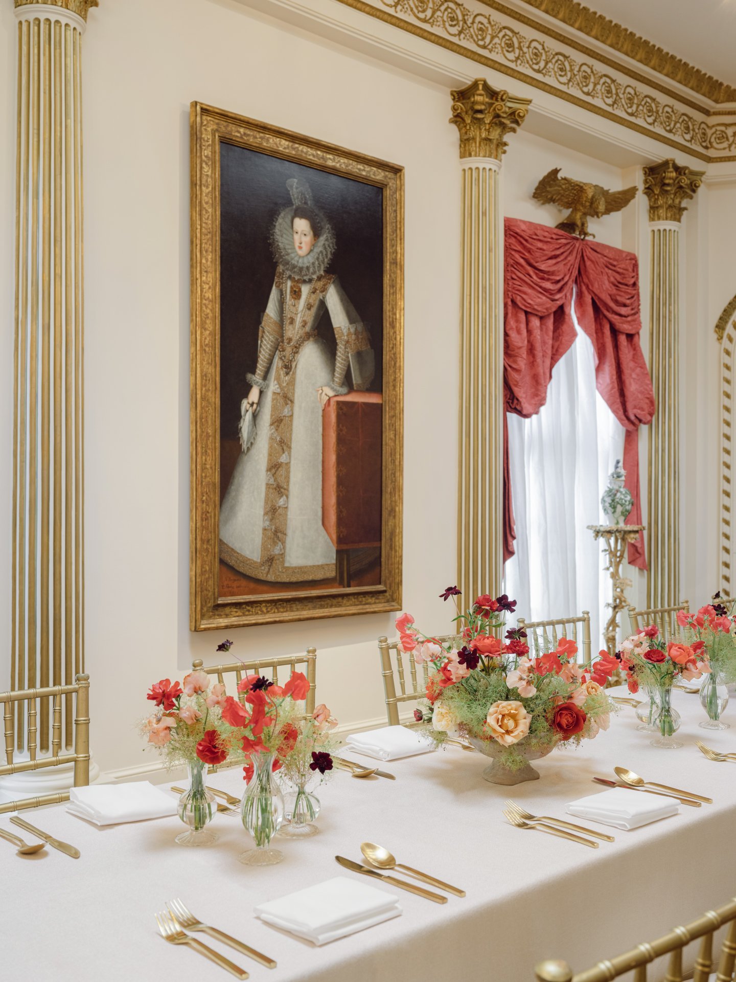 Contemporary garden-style floral centerpieces set on a fine dining table at the Rienzi Museum, framed by gold seating and historic European art.