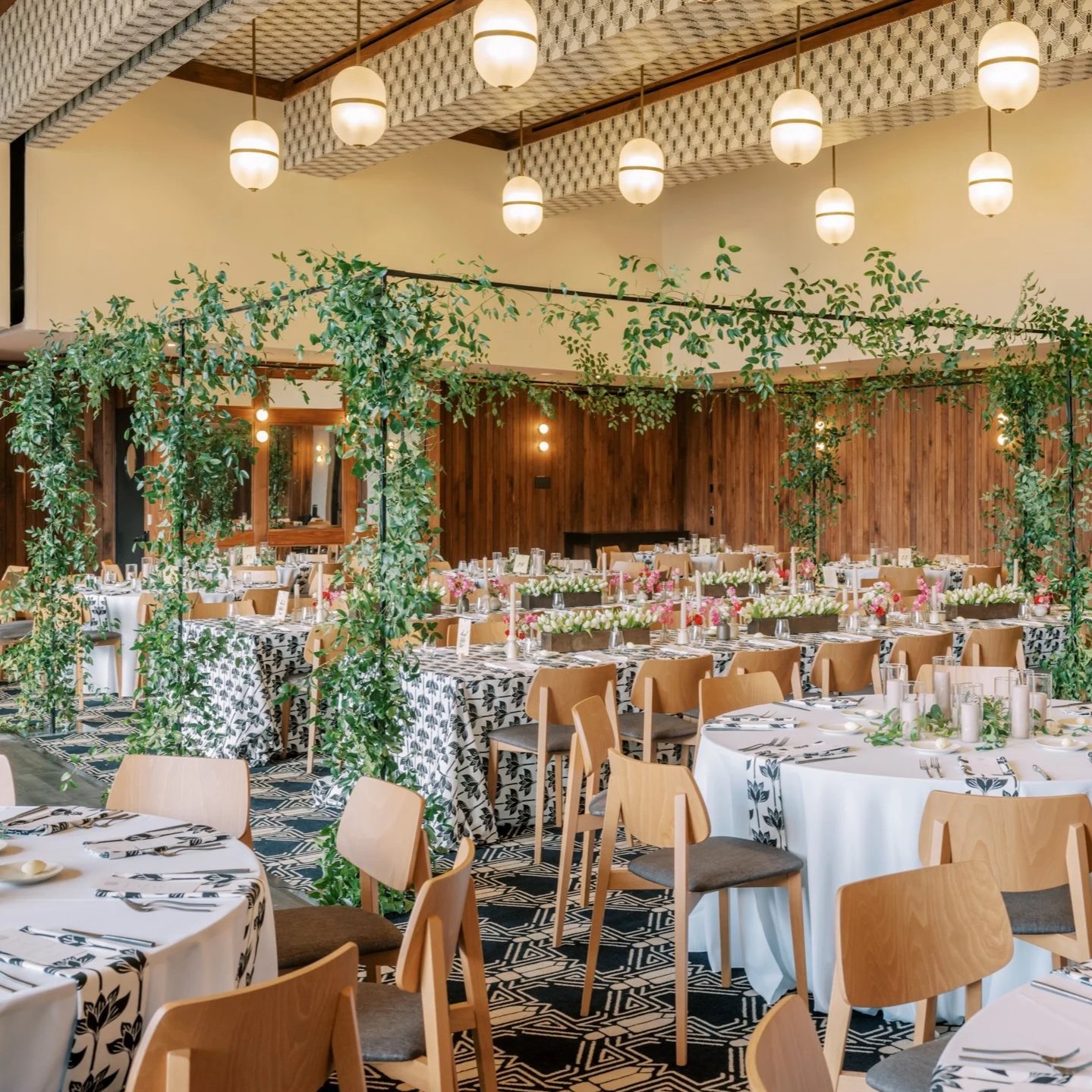 Editorial wedding reception featuring suspended greenery installations, long banquet tables, and refined floral table settings in the ball room of the Austin Proper Hotel