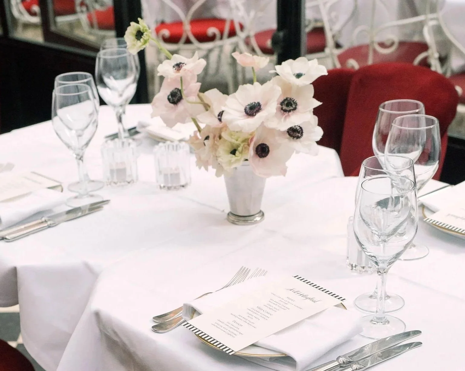 Soft blush anemone centerpiece in a silver julep cup atop an elegant tablescape at Hôtel Particulier by The Petaler Floral & Events Co., known for art-driven wedding design for American weddings in France.