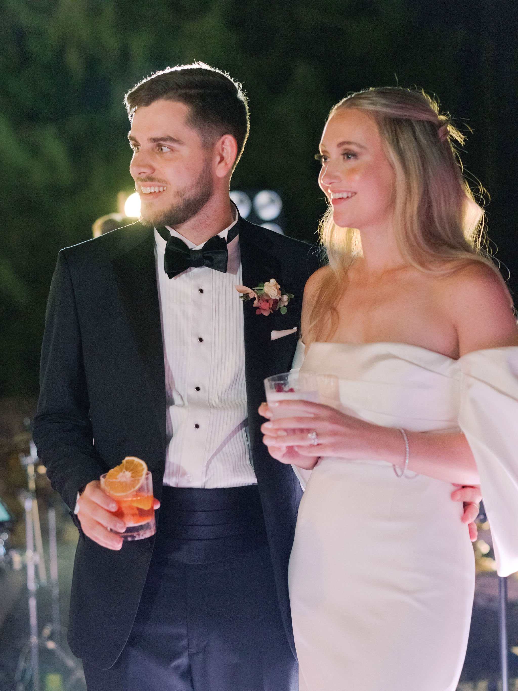 Newly married couple enjoying a candid evening moment with signature cocktails at their Domaine des Halles reception, with florals by The Petaler Floral and Events Co., wedding planner in France.