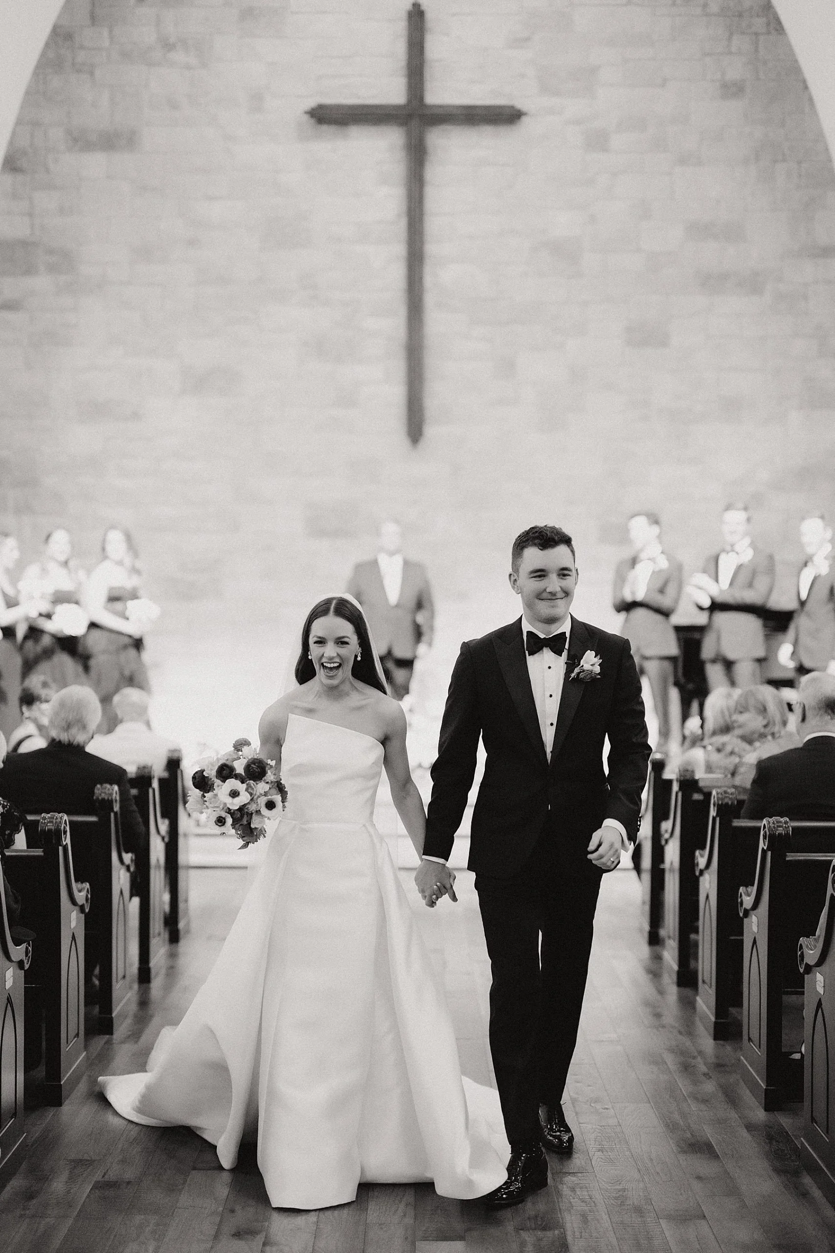 Bride and groom walking hand in hand down the aisle after their wedding ceremony, captured in a black and white portrait