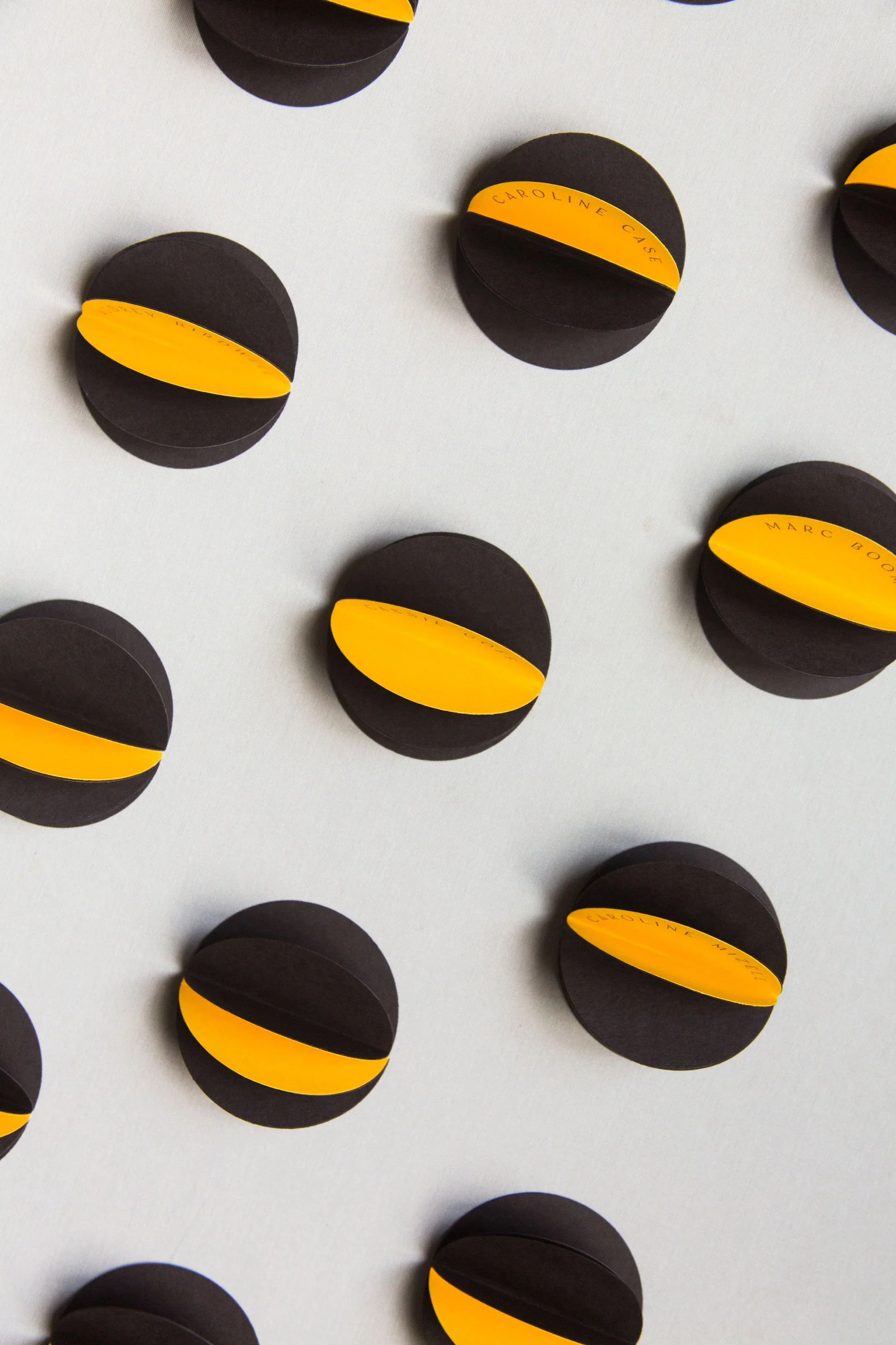 Editorial flatlay of oxblood-and-mustard accordion place cards in a precise grid, designed by The Petaler Floral & Events Co., a luxury planner and creative director for American destination weddings in France.