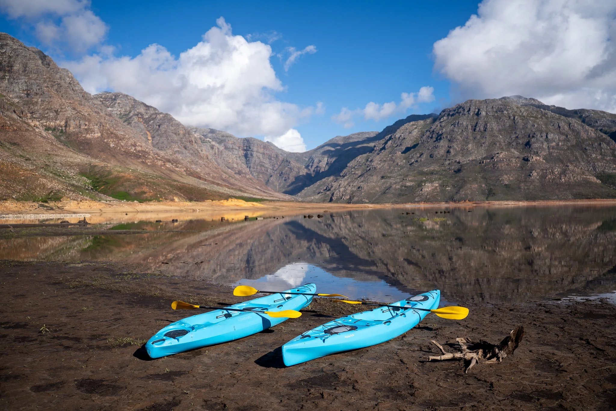 Yellow kayak paddle in water with industrial buildings and boats in the background.