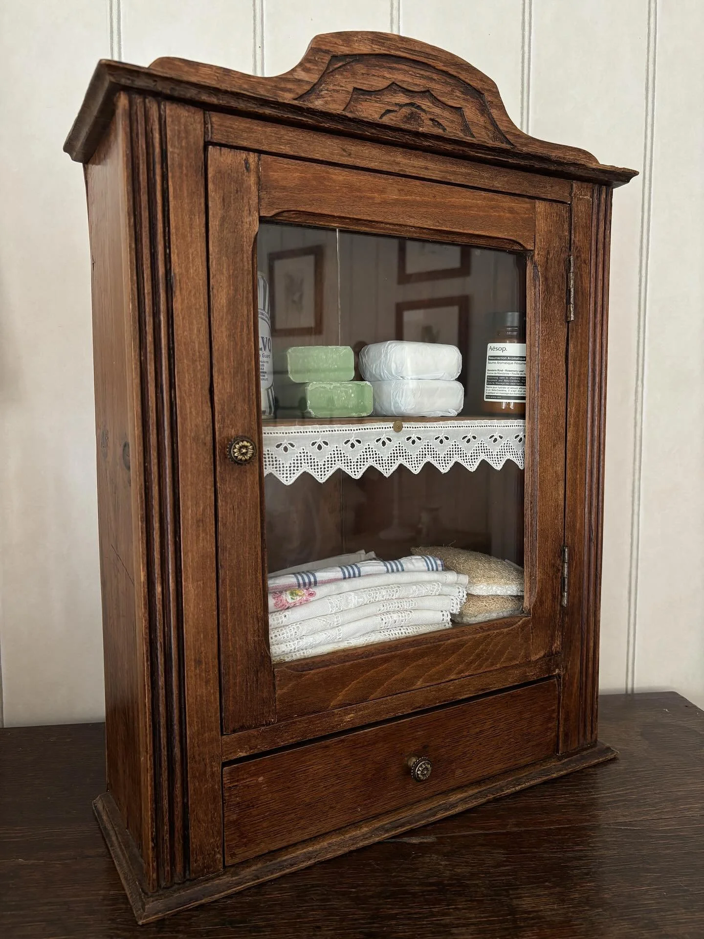 FOR SALE A gorgeous vintage French wooden cupboard. Two tiered shelves behind a glazed door with a little drawer beneath. The shelf is decorated with a length of the prettiest vintage cotton lace. It could be used as a tabletop cupboard or hung from 