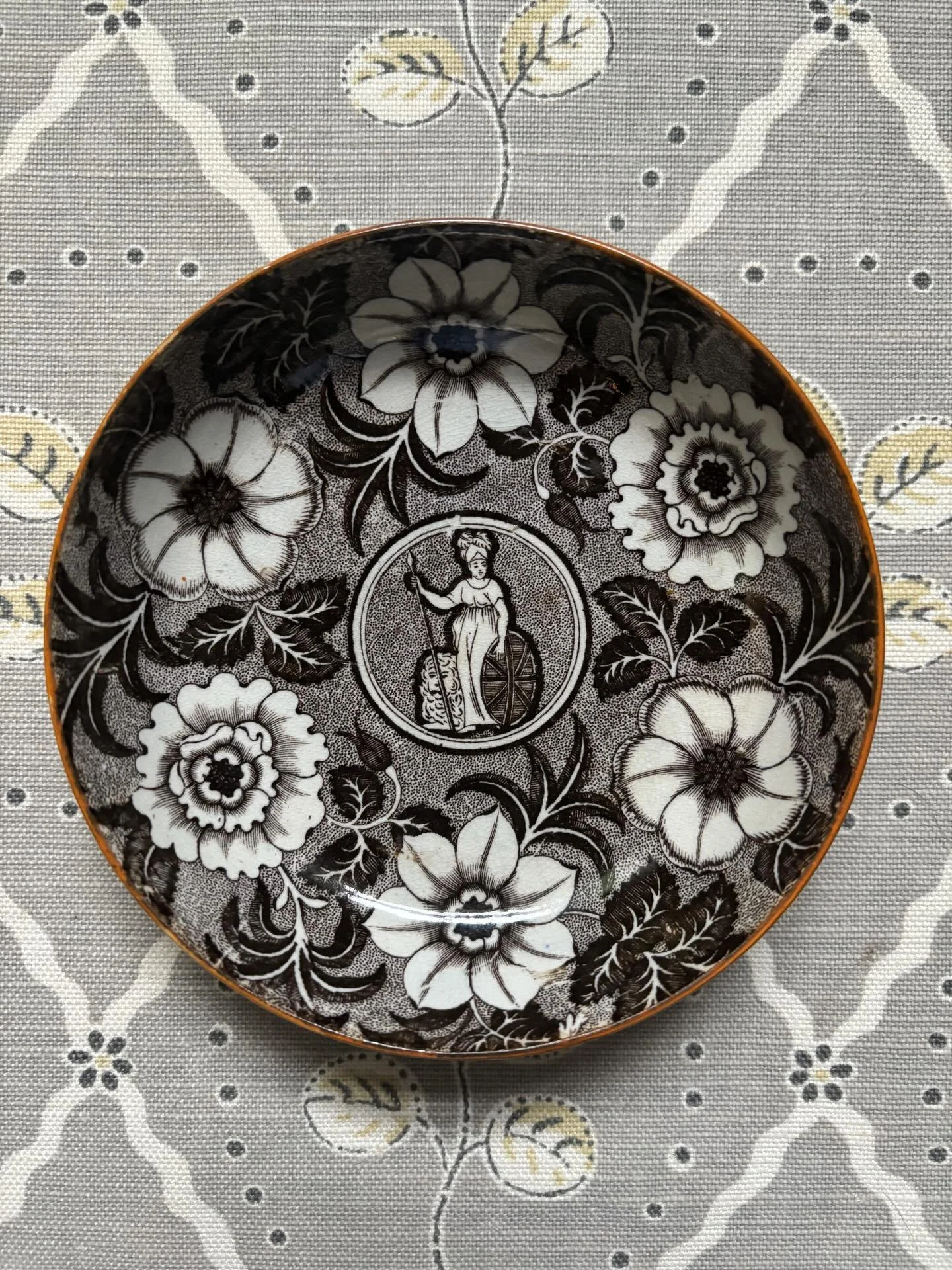 SOLD 🌟 A scarce Georgian transfer printed pearlware saucer or small dish, circa 1800. It depicts Britannia with shield and staff standing beside a lion. It is a rare depiction of Britannia without a trident or helmet, emblems that came later on. The