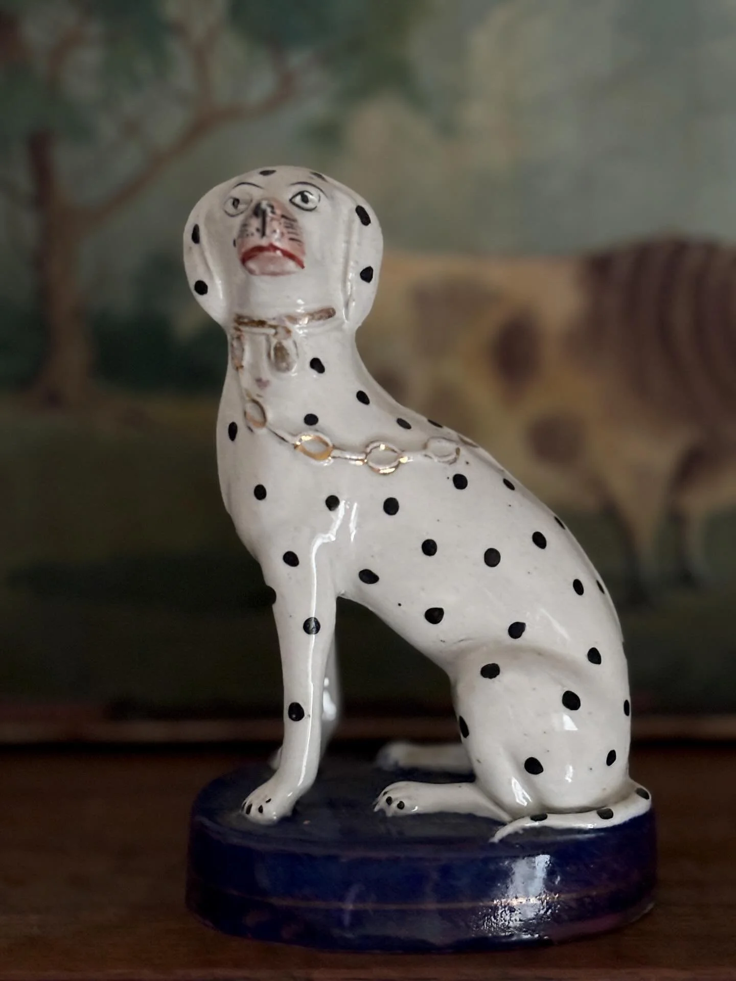 PENDING A super antique Staffordshire figure of a Dalmatian, circa 1880. It is a particularly lovely example of a classic piece of Staffordshire pottery: an elegant hound with a typically expressive face, sitting on a cobalt blue base with gilt detai