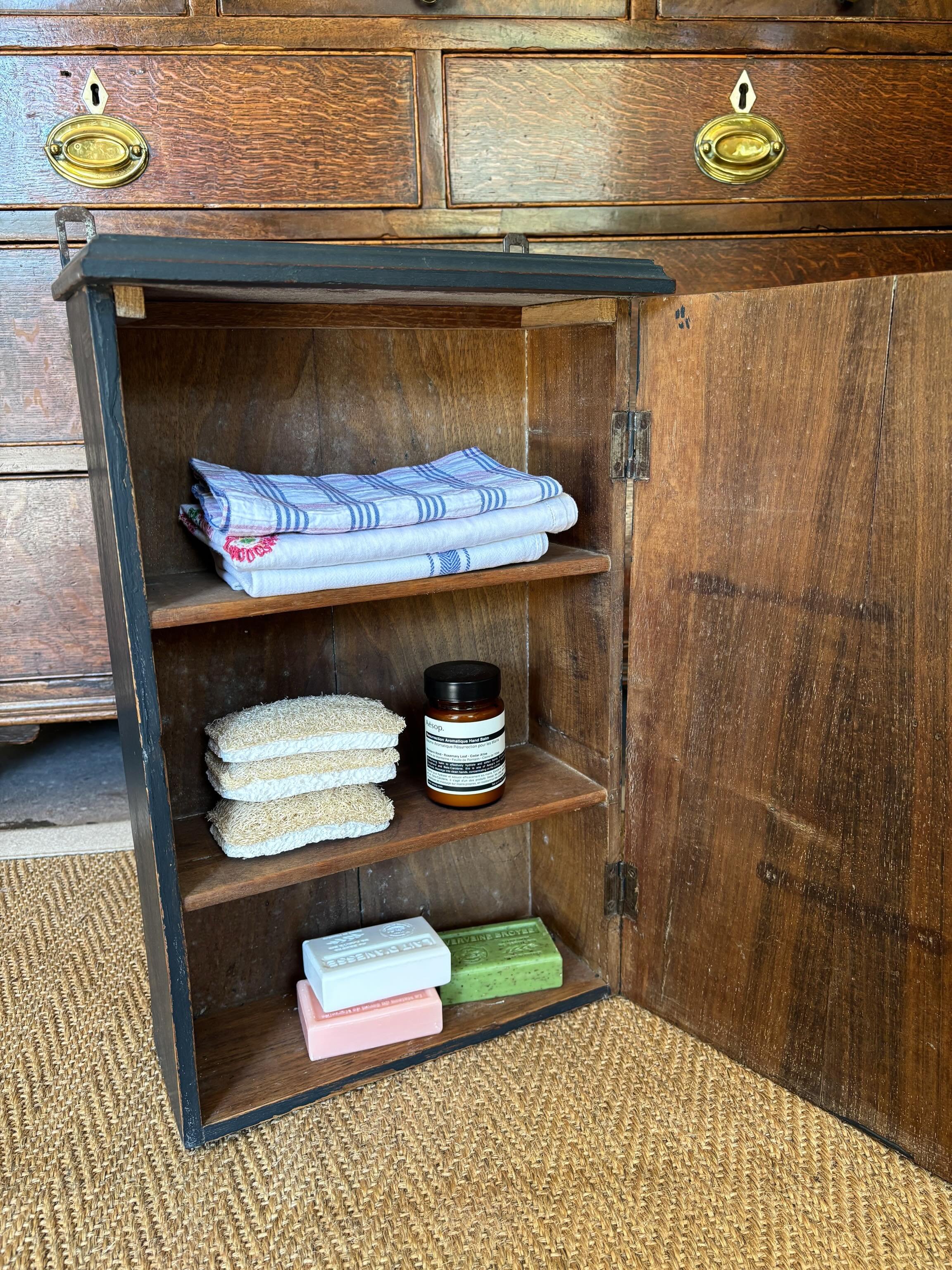 FOR SALE An excellent vintage painted wooden wall cupboard in a midnight blue colour. It has a plain wood interior with three shelves and the door has a working lock with key. It is in very good solid condition. 

Two brackets at the top for hanging.