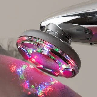 A close-up of a device emitting colorful laser light reflections on a surface.