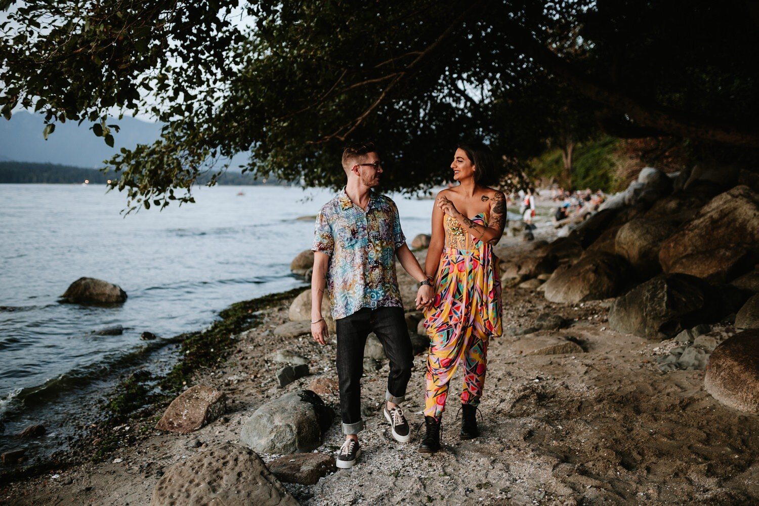 Engaged couple walking by the shore at Kitsilano Beach during their engagement session.
