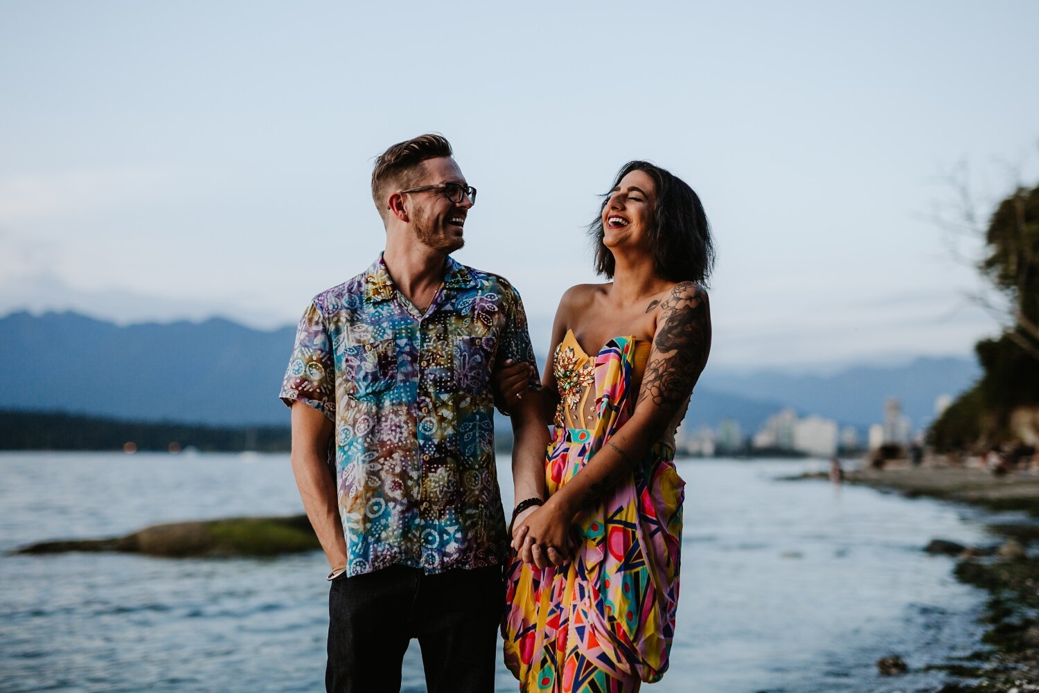 Engaged couple laughing at Kitsilano beach during their engagement photoshoot.
