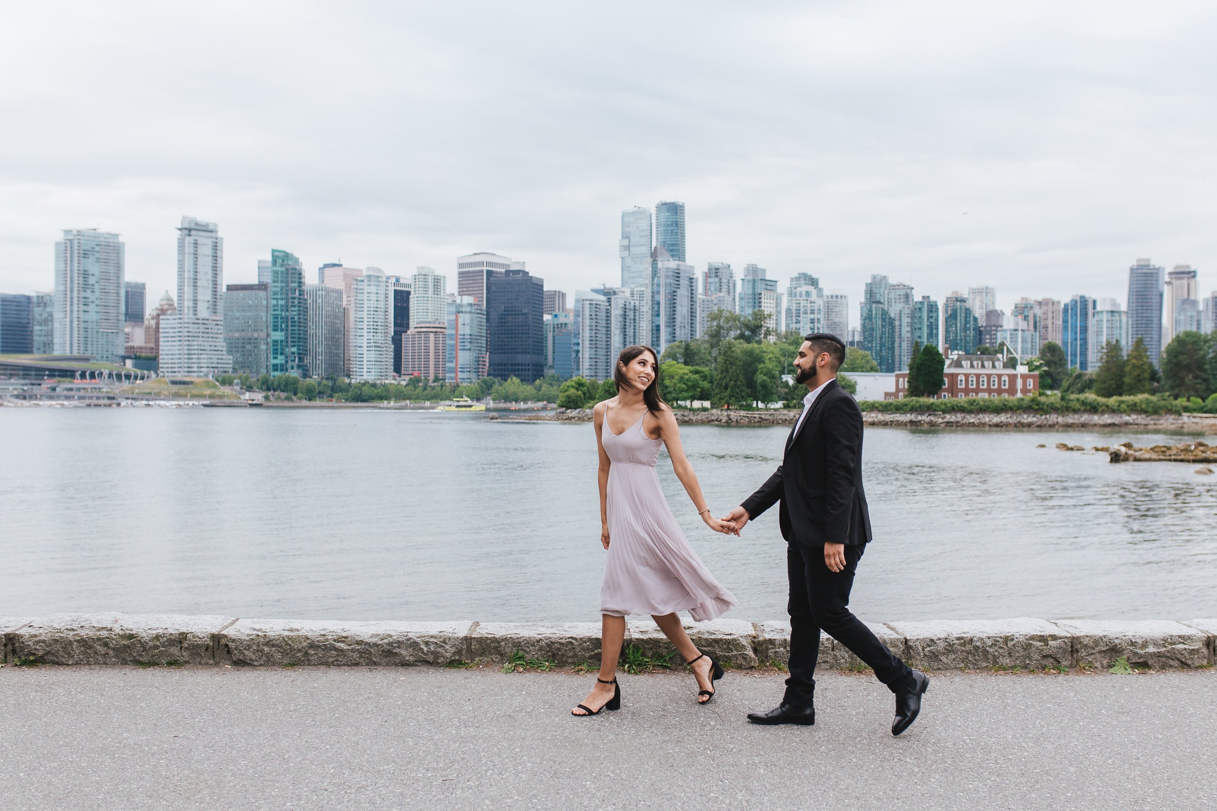 Engaged couple walking on the seawall at Stanley Park.