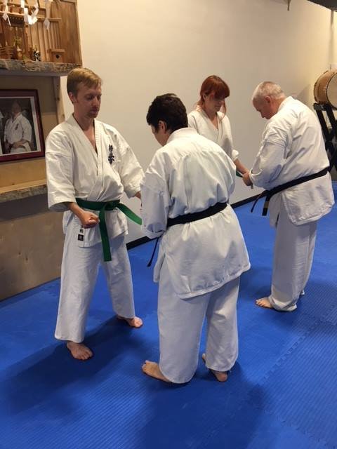 Ryan Layman, Instructor at Aranami Dojo in Honolulu, Hawai’i, receives his green belt from Tom and Toni Flynn of Green Mountain Dojo in Vermont. Photo from 2018.