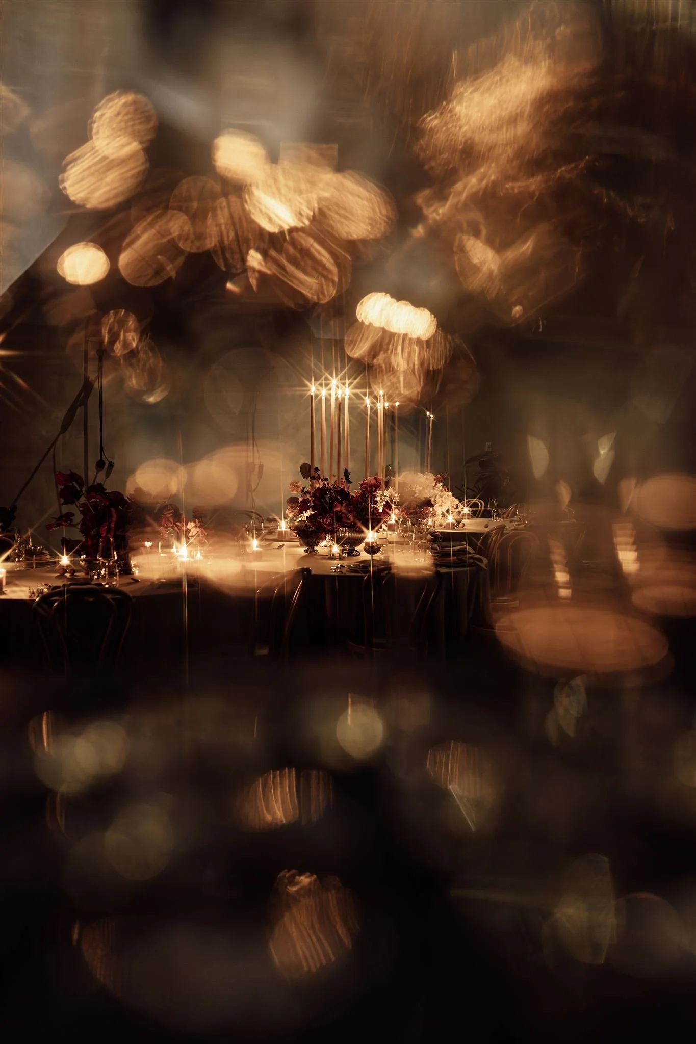 Elegant event table decorated with flowers and candles, viewed through a blurred, bokeh effect.