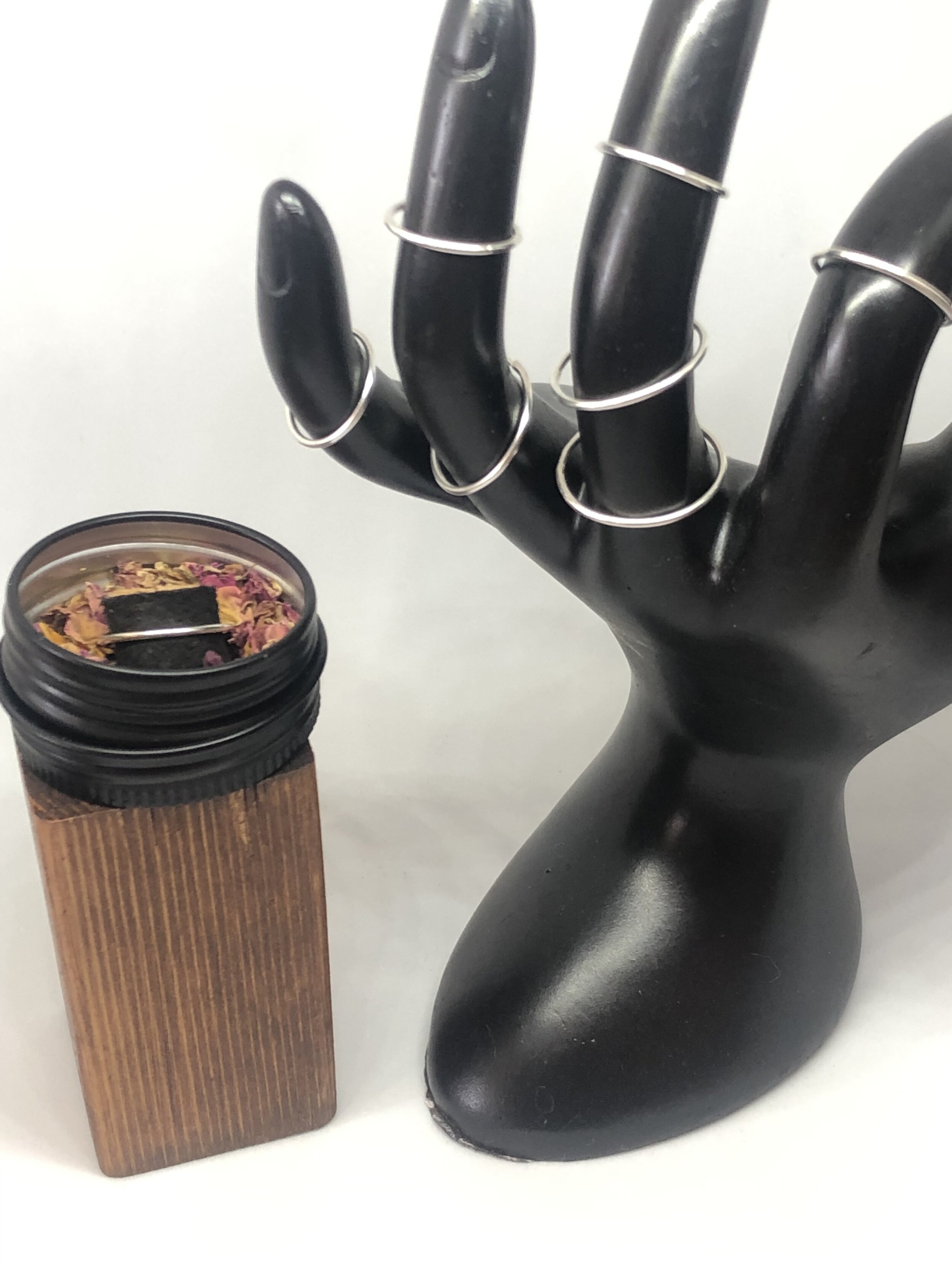Multiple sterling bands on a black hand form, different sizes and thicknesses stacked on each finger.