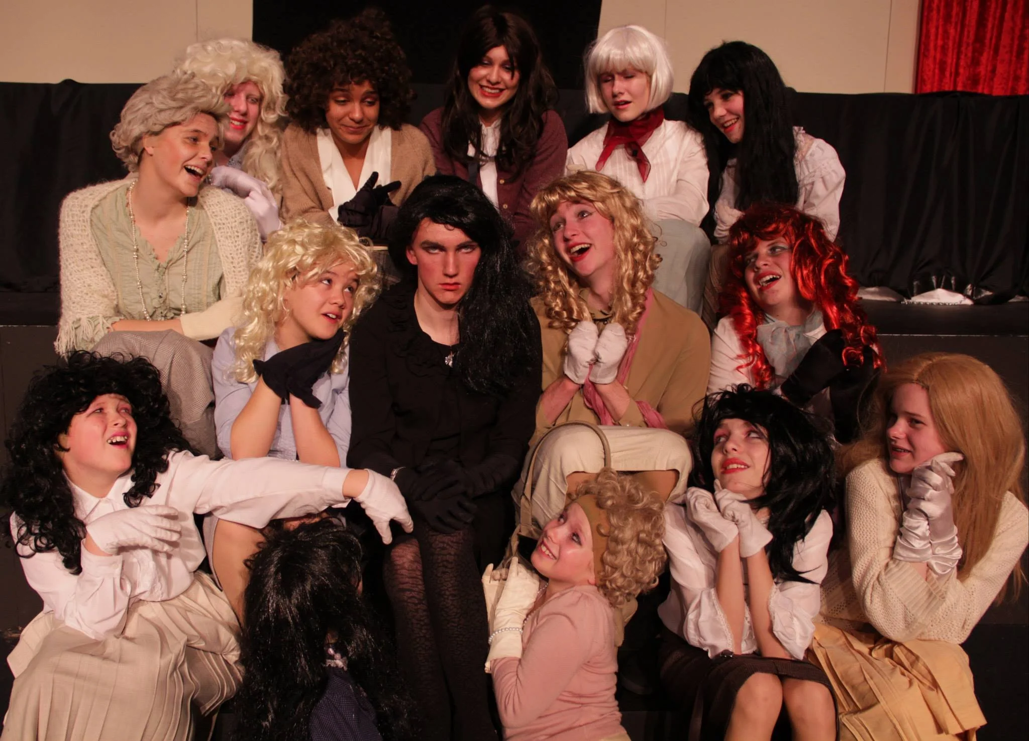 Group of people dressed in costumes resembling different characters, gathered on a stage, some smiling and some making funny faces.