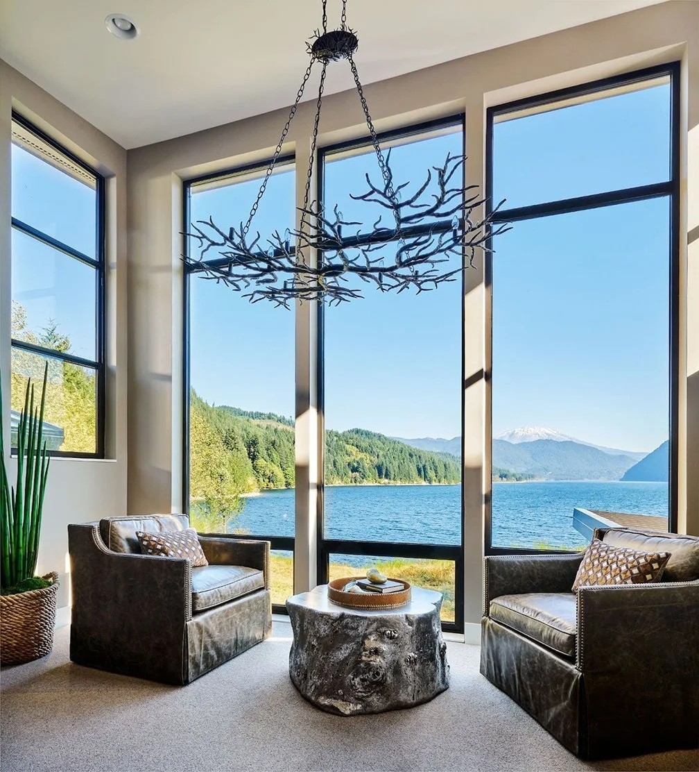 A spacious sitting area with chandelier and a view of a lake.