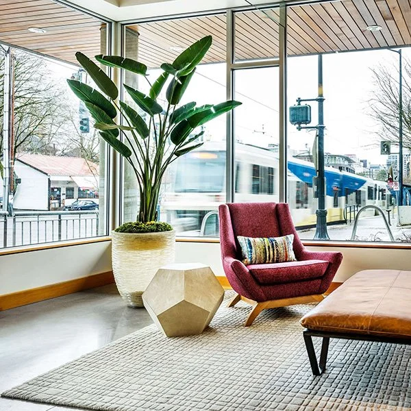 A pink chair sitting on a patterned rug next to a geometric side table. 