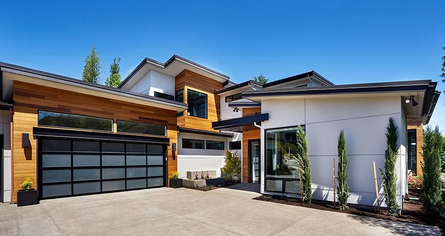 The exterior of a modern home with glass garage doors.