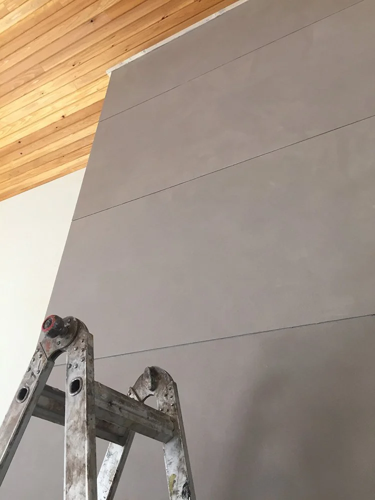 A ladder in front of a fireplace that is receiving a faux finish.