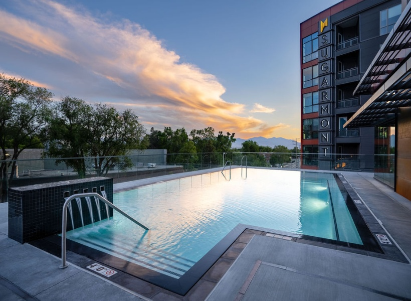 Rooftop swimming pool overlooking trees and mountains at sunset at the SugarMont hotel.