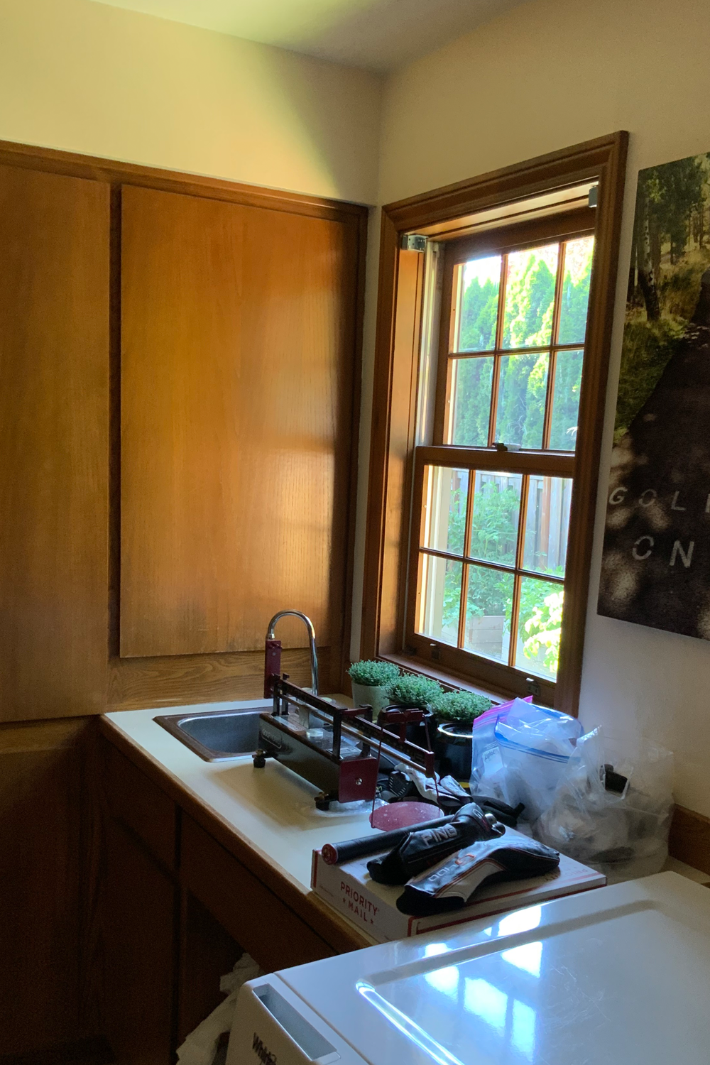 Portland laundry room before remodel, dark oak cabinets and cluttered countertop.