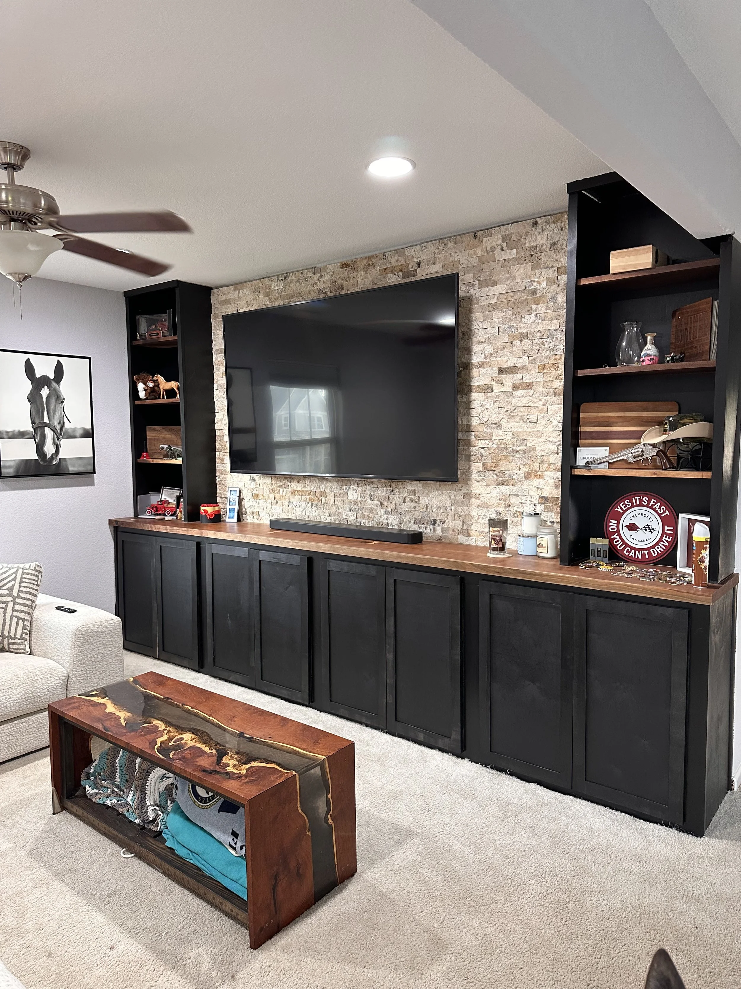 Loft built in with walnut top & shelves with accent rock behind tv