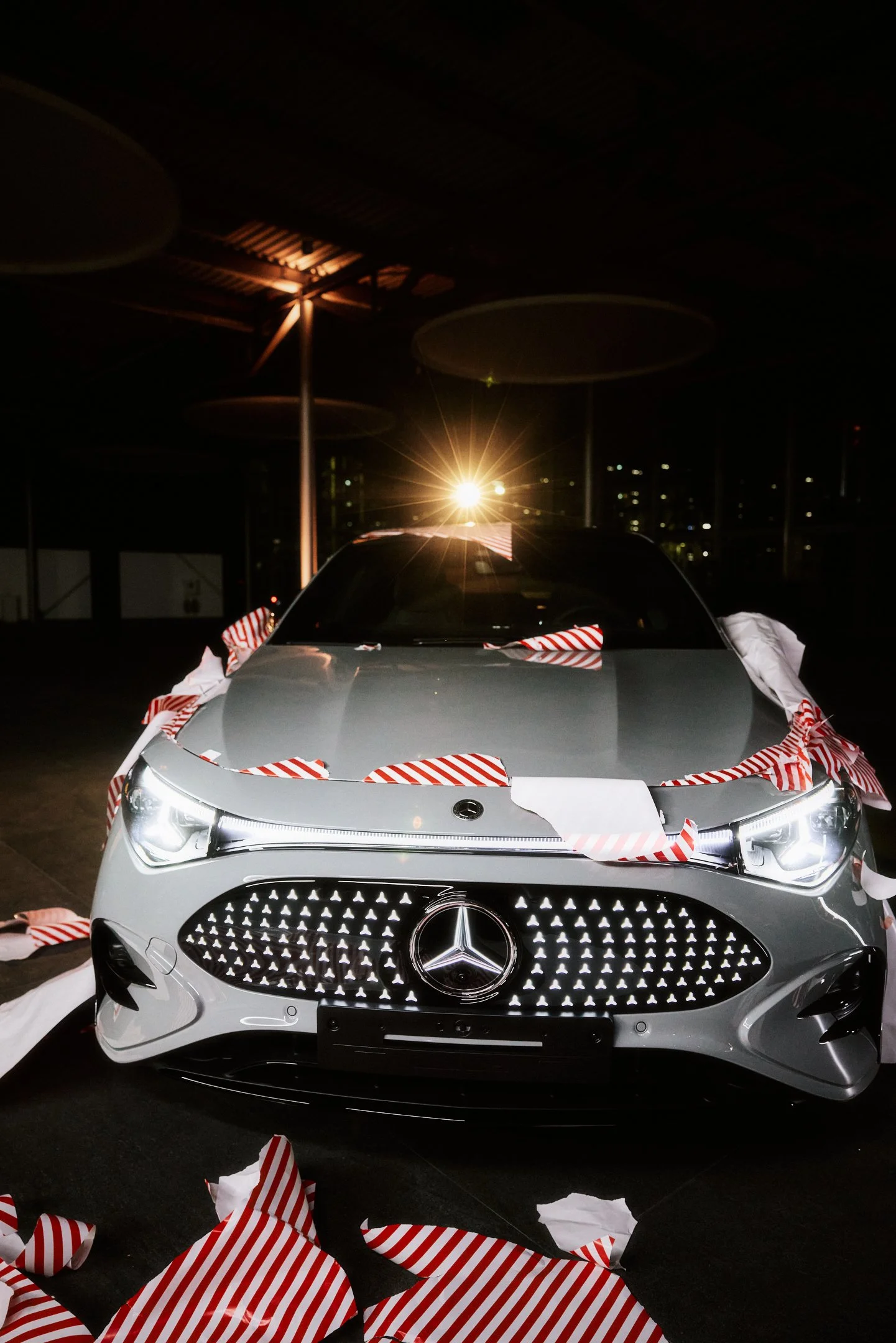 Hero Shot Fahrzeugfront im Showroom, Geschenkpapier Reste als Kampagnen Look, starkes Gegenlicht.