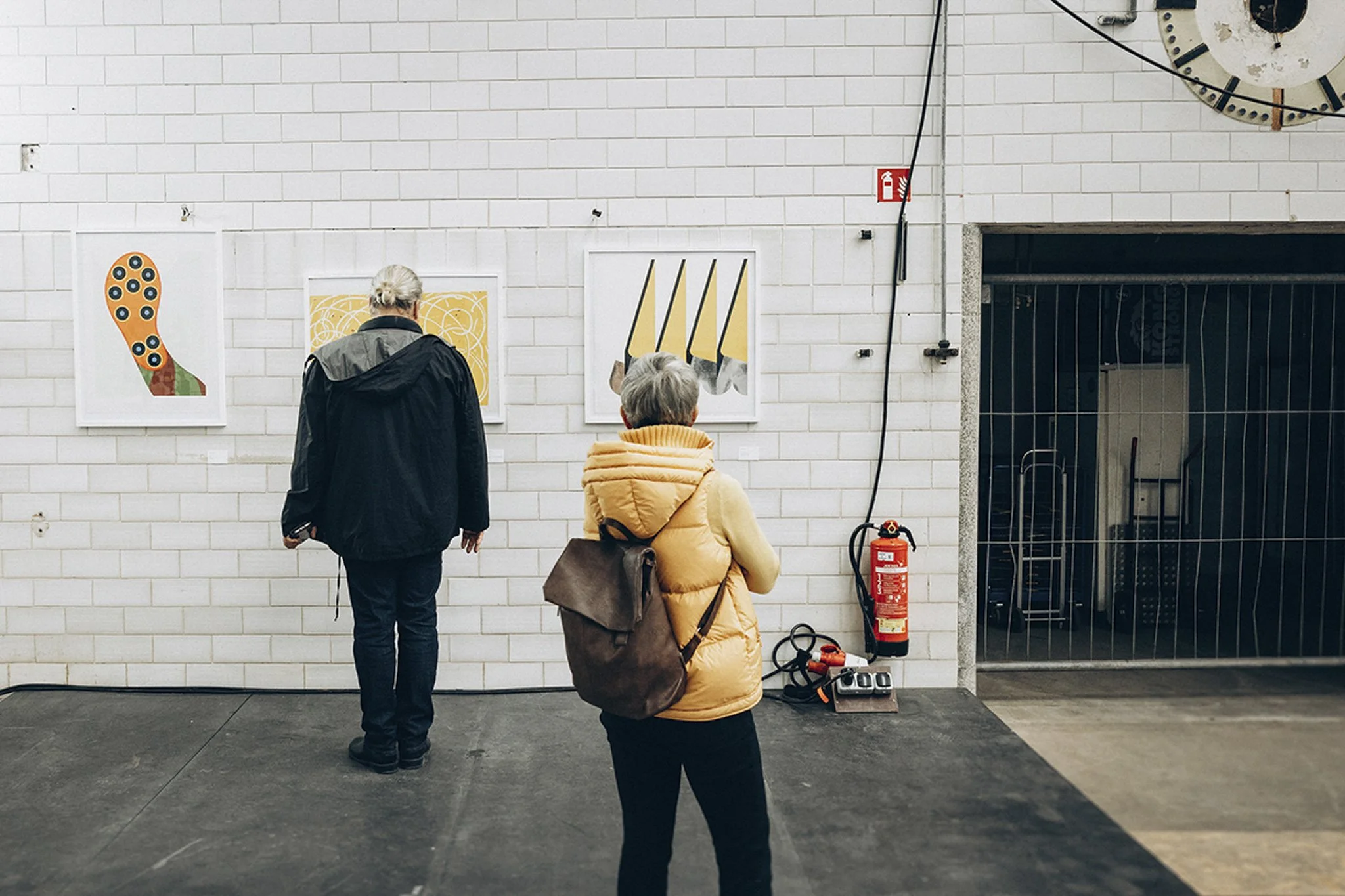 Besucher betrachten gerahmte Kunst an Wand in Industriehalle, Publikum im Raum bei Kunst Ausstellung und Auktion, Eventreportage Stuttgart