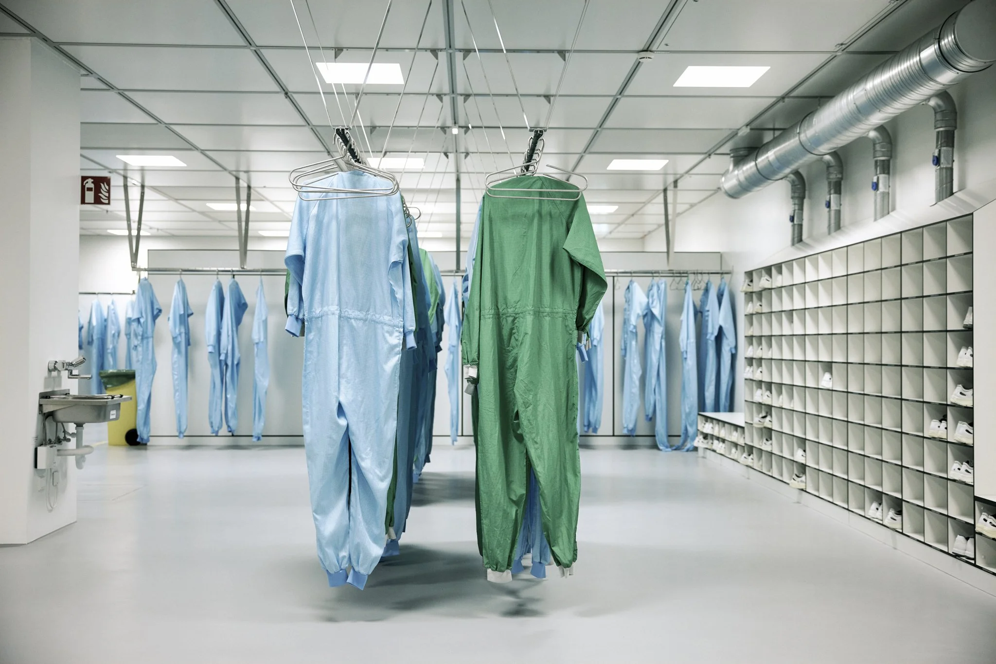 Unternehmensfotografie im Reinraum, hängende Schutzanzüge und Ordnung, technische Produktion im Hintergrund.