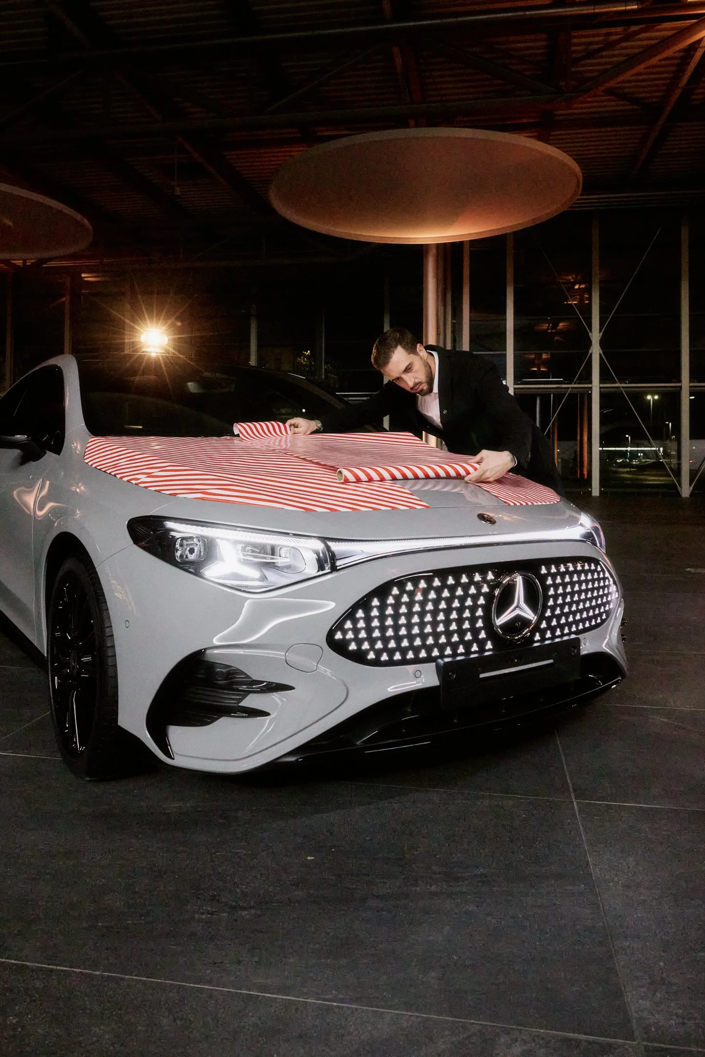 On site Motiv für Social Campaign, Fahrzeugfront im Showroom, Geschenkpapier wird über die Motorhaube ausgerollt.