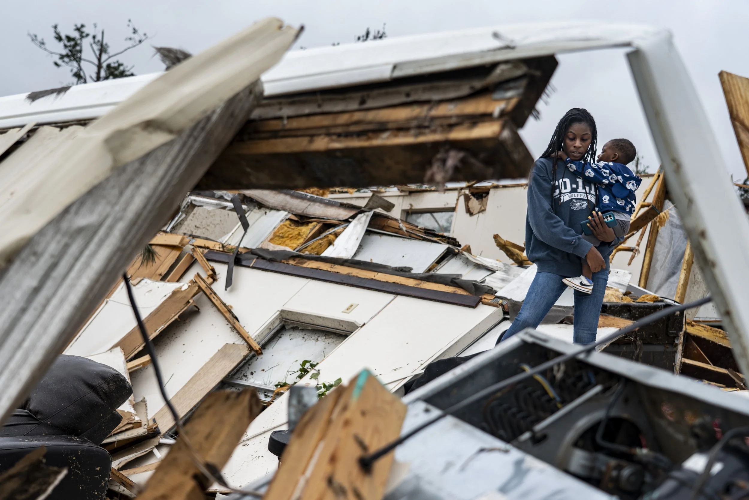 Miah Amos holds her son Bentley Earls, 2, as they look through their home at a mobile home park off of U.S. Highway 51 in Bogue Chitto, Miss., in Lincoln County on Thursday, May 7, 2026. A tornado went through the area the previous night injuring sev