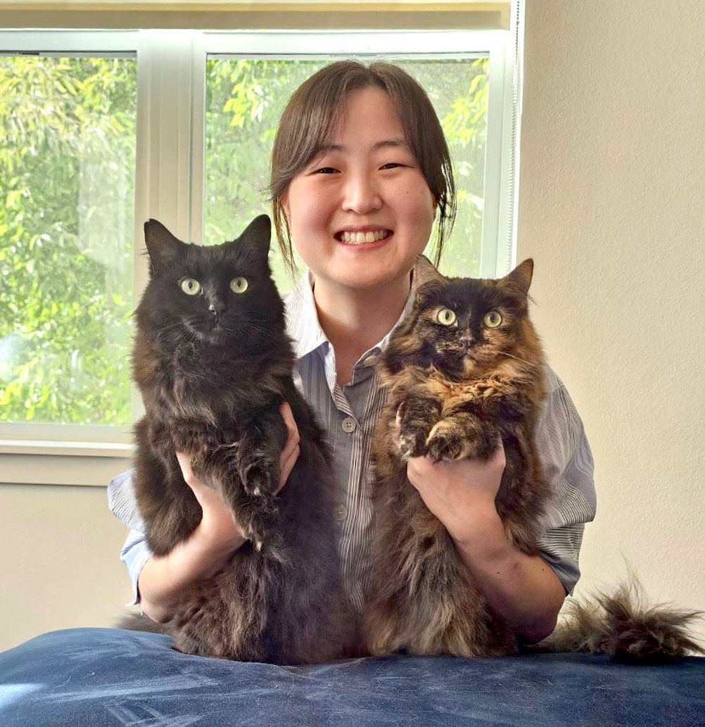 Dr. Kim smiles as she holds her two long-haired cats