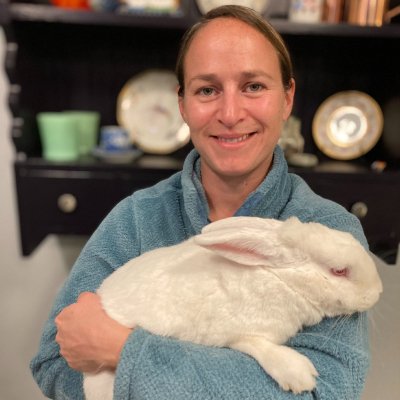 Image of employee Grace holding a rabbit in her arms wearing a blue sweater