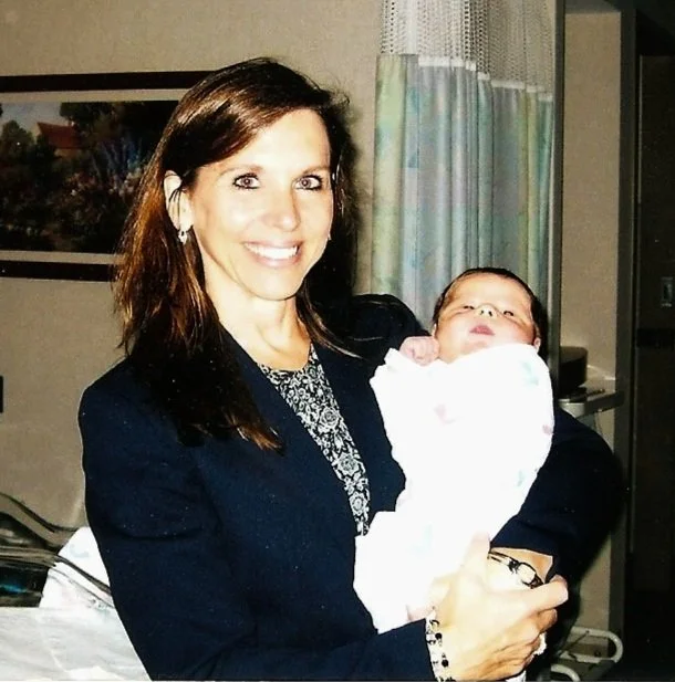 Jacquelyn Paykel, MD, obstetrician holding a baby in a hospital room.