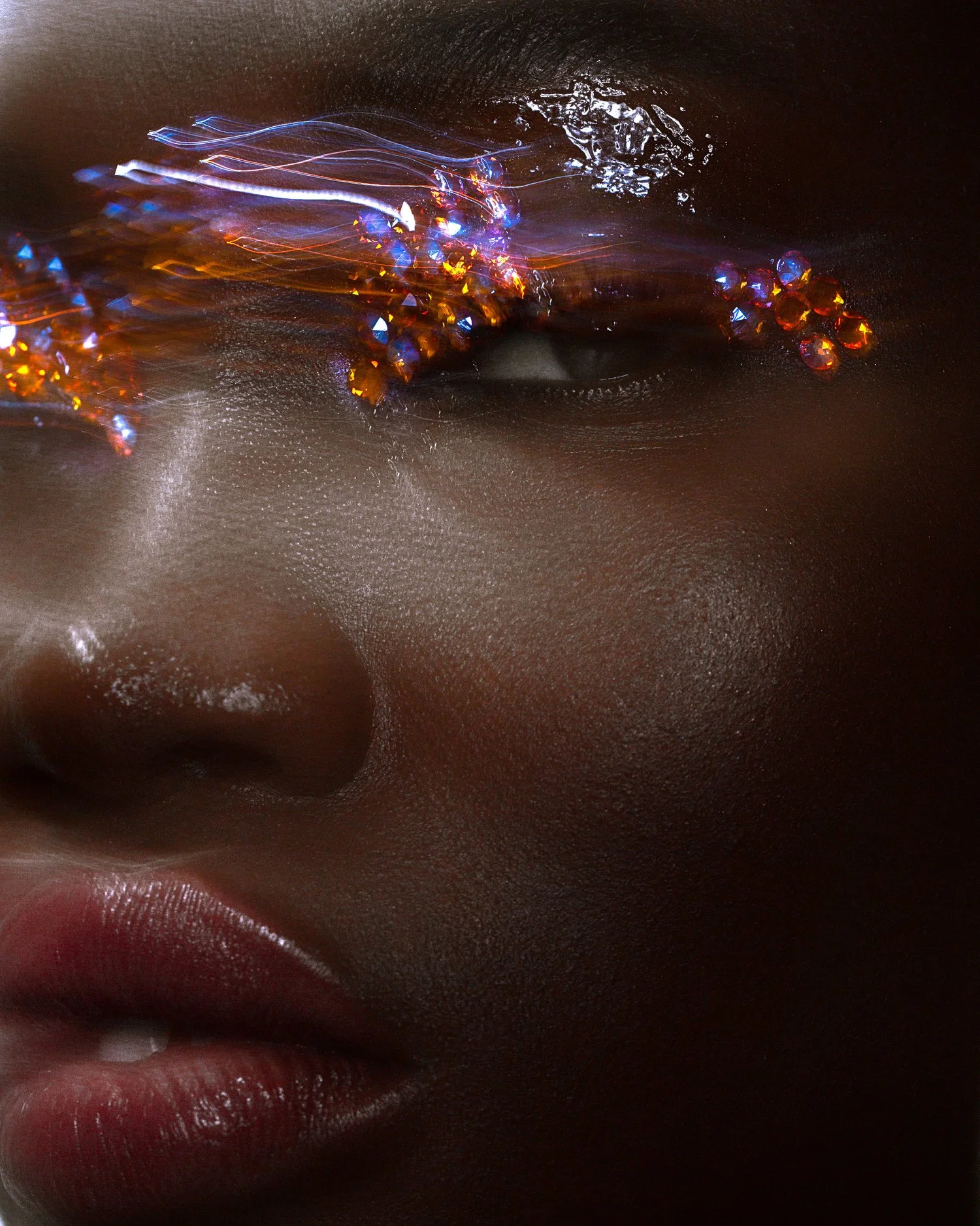 Close-up of a person's face with dark skin, wearing eye jewelery with gems and light streaks, showing only the nose, lips, and part of the eye area. Beauty Photographer Los Angeles.
