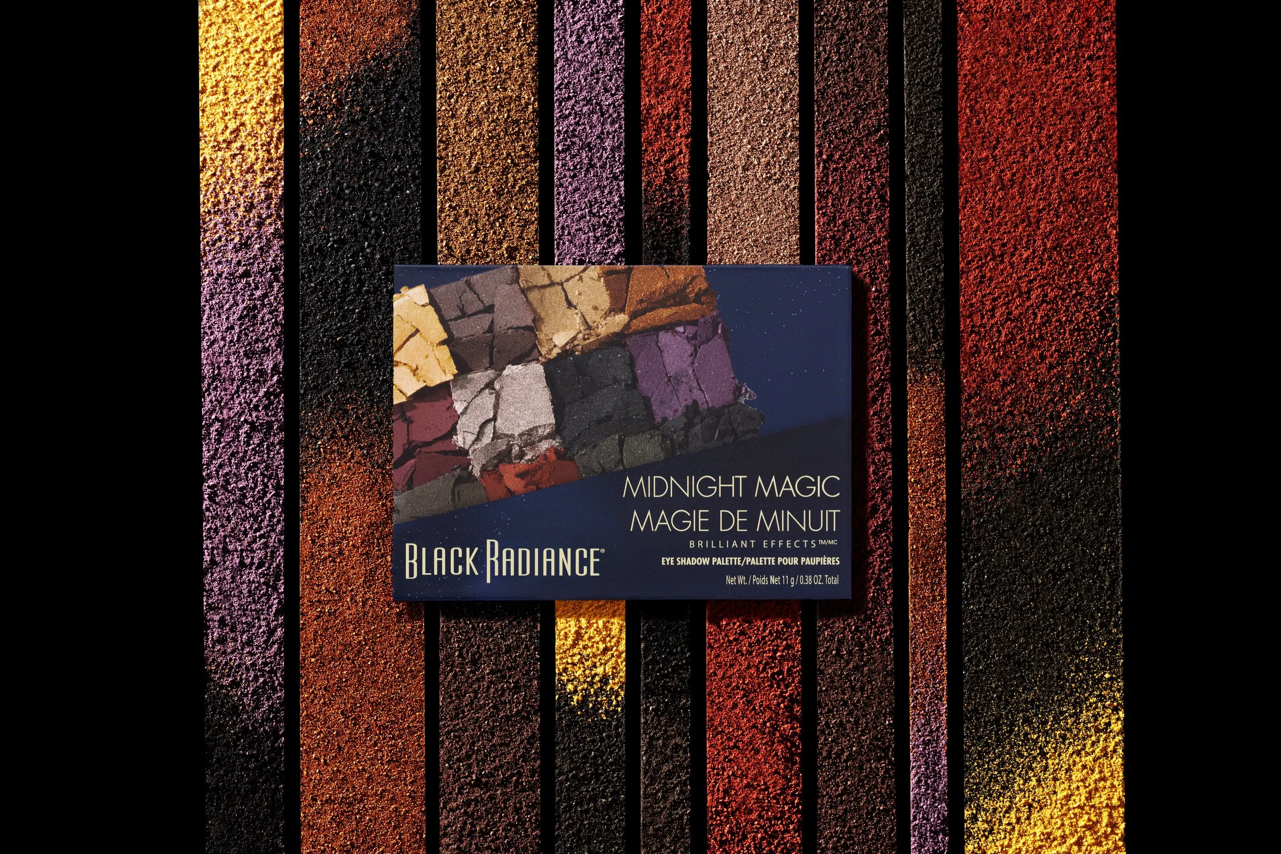 Photo of a Black Radiance eyeshadow palette called Midnight Magic, placed on a textured, striped surface with rainbow-like colors. Product photography Los Angeles.