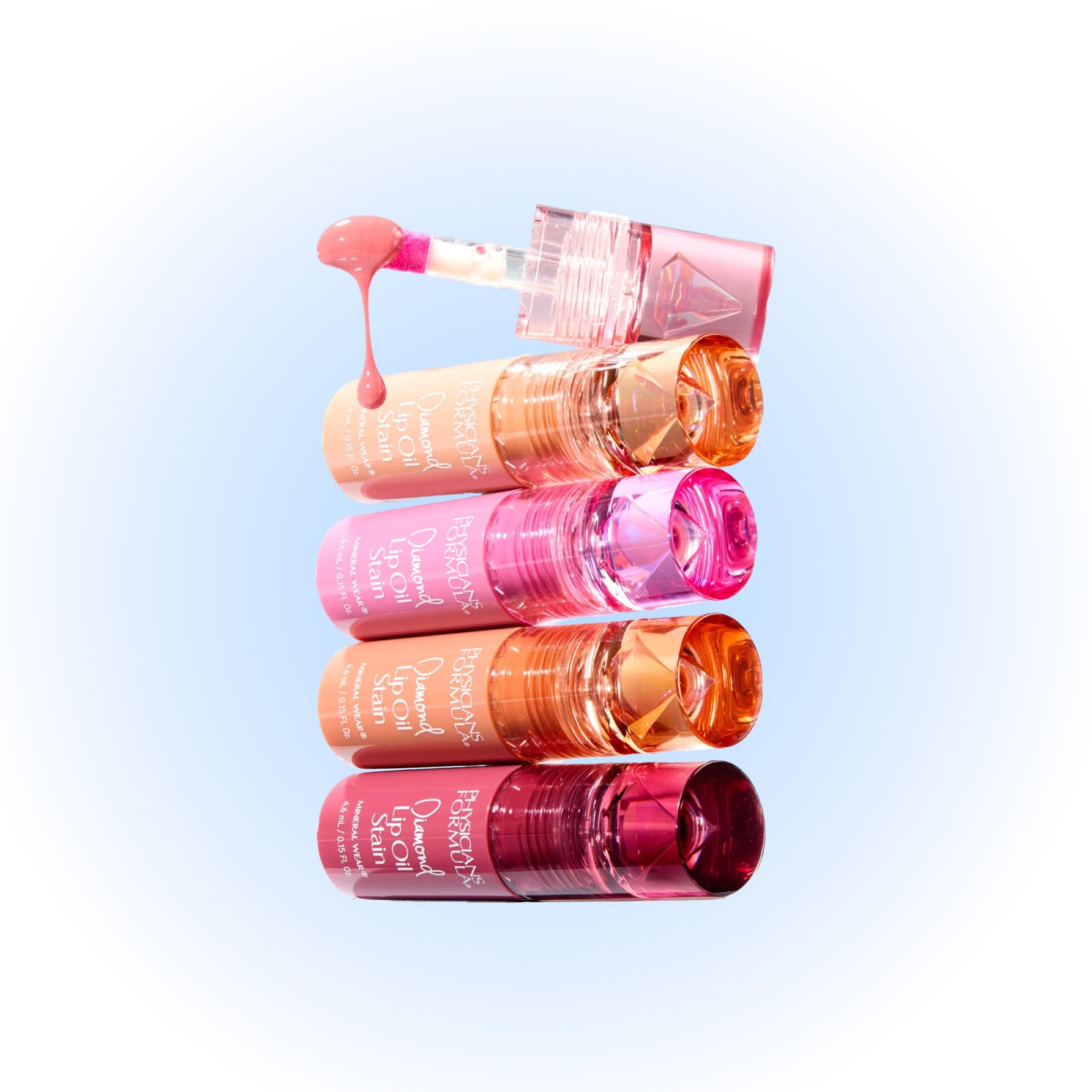 Four bottles of hydrating lip oils stacked vertically, with a dropper applying lip oil at the top, against a light blue background. Product photography Los Angeles.
