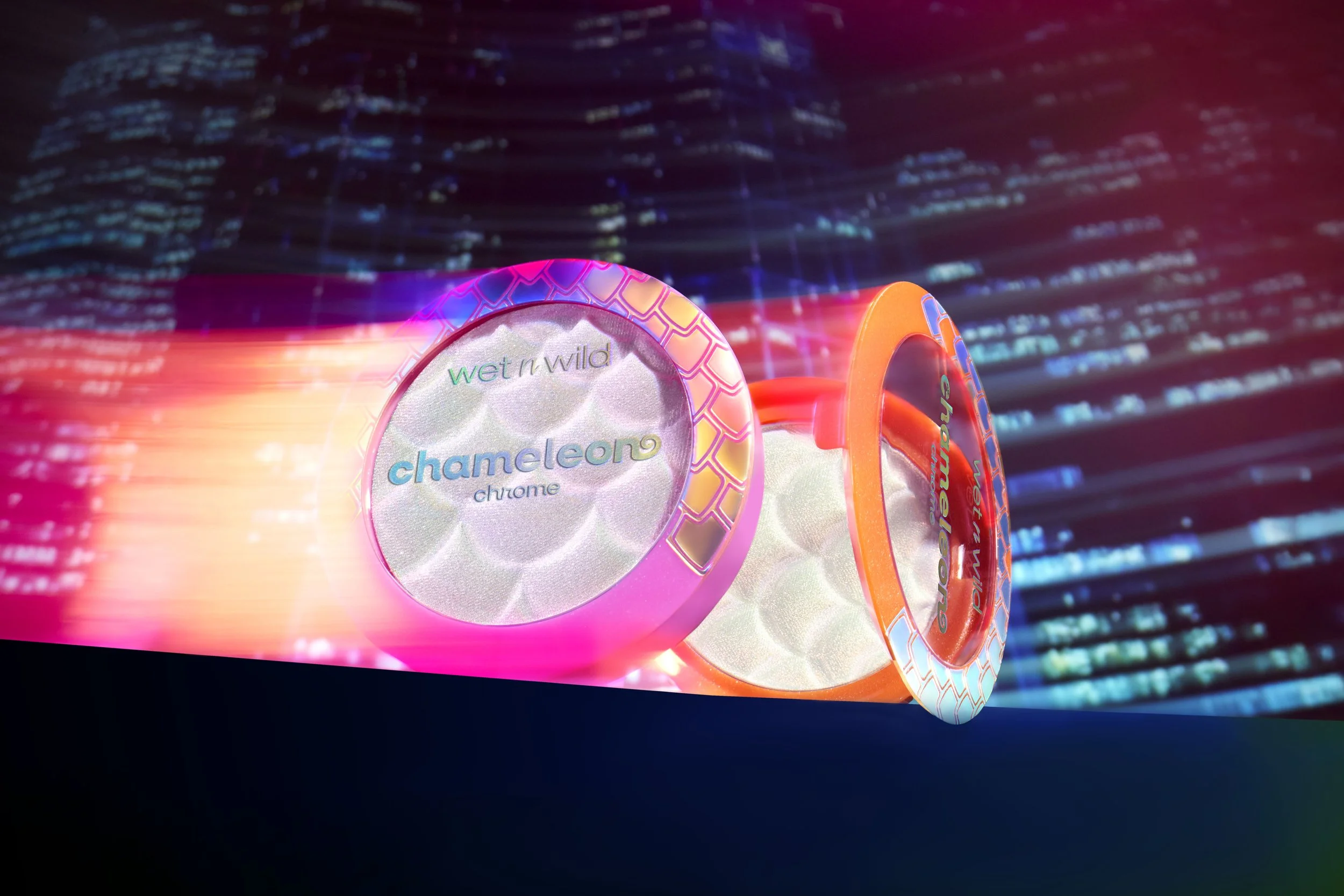 Two colorful containers of Wet n Wild Chameleon Chrome eyeshadow with a neon cityscape background. Product photography Los Angeles.