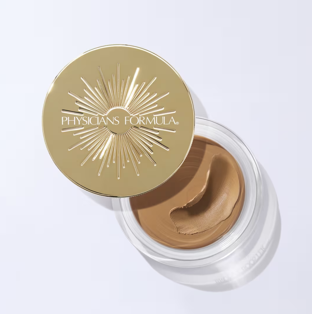 Open container of Physicians Formula foundation with the lid partly covering the product, showing the beige makeup inside.