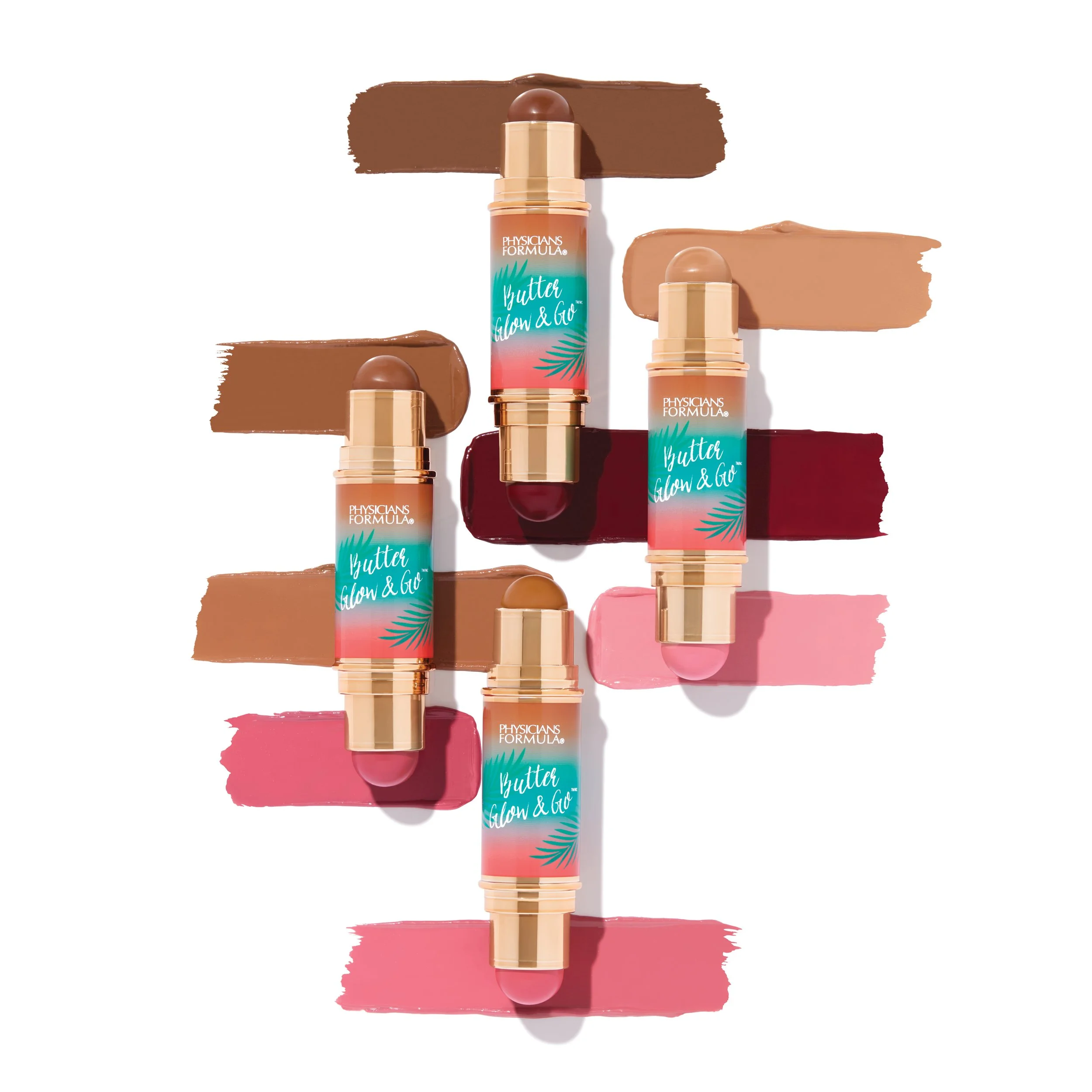 Four tubes of Physicians Formula Butter Glow & Go highlighters with swatches of different shades in tan, nude, pink, and reddish-brown colors spread around them. Product photography Los Angeles.