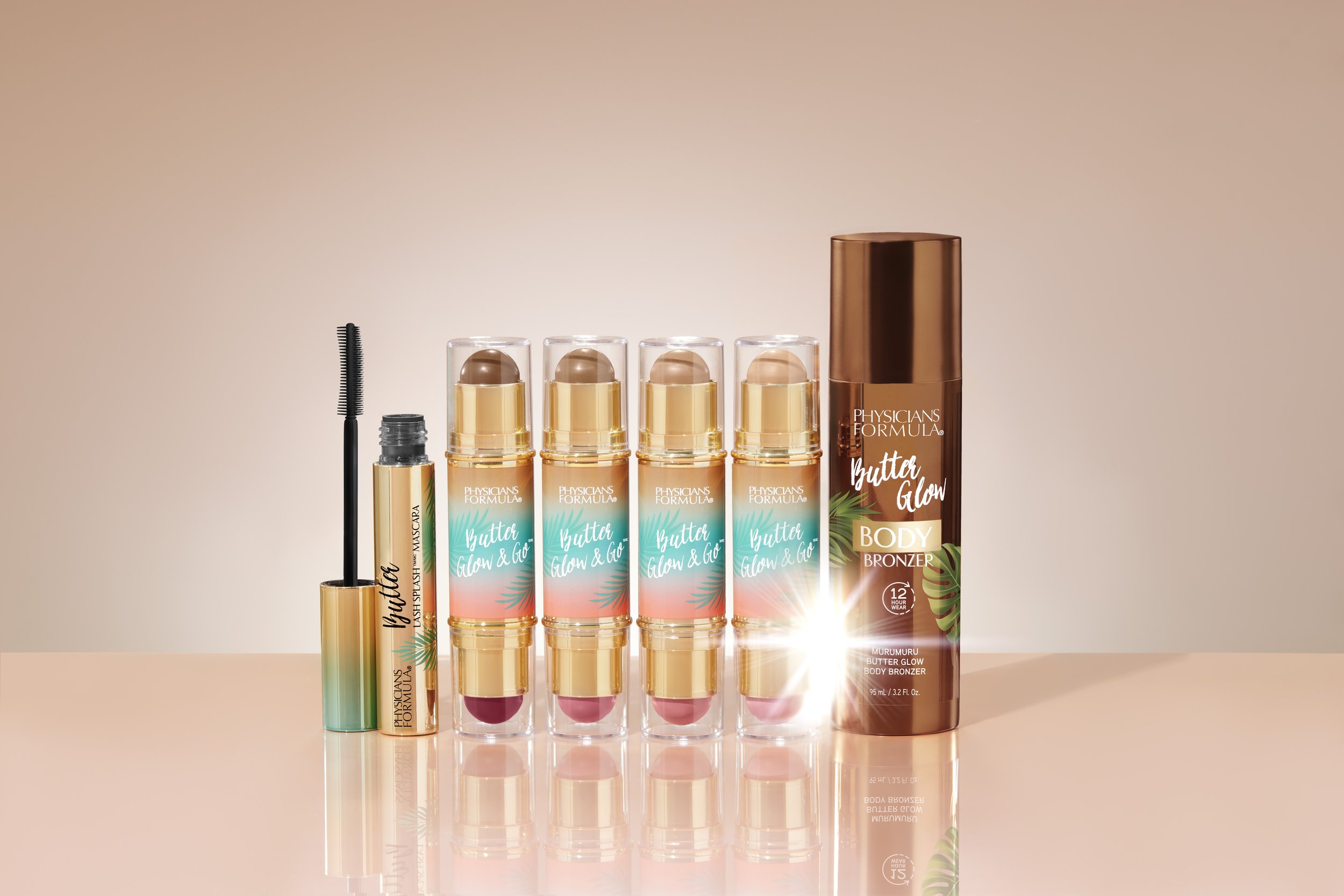 Collection of Physician's Formula Butter Glow & Go products including a mascara, four highlighter sticks, and a body bronzer, all in pastel and brown packaging with a soft pink background. Product photography Los Angeles.
