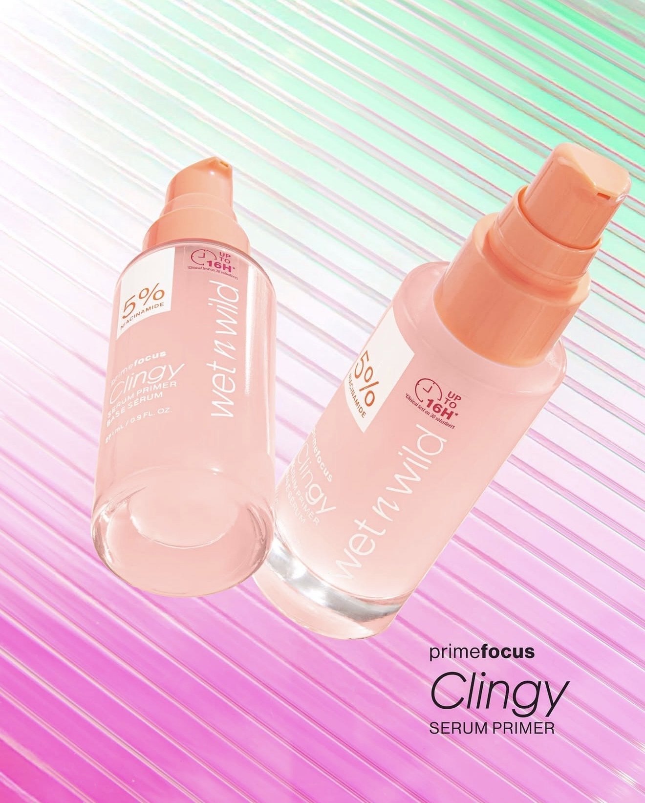 Two bottles of Prime Focus Clingy Serum Primer, one lying down and one standing, on a colorful striped surface with pink, green, and white colors, with text indicating the product name. Product photography Los Angeles.