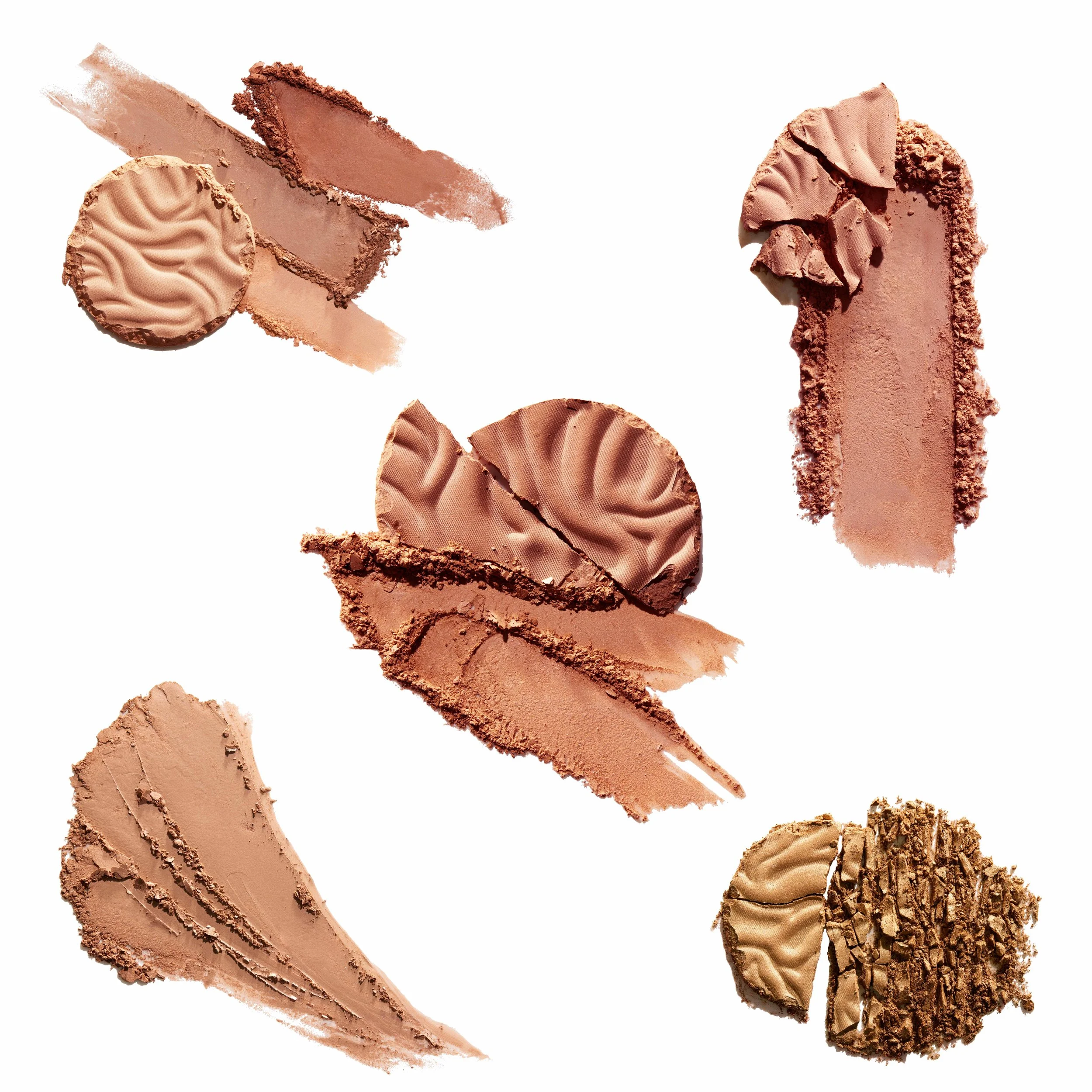 Various shades and textures of crushed and smeared makeup powders arranged on a white background. Product photography Los Angeles.