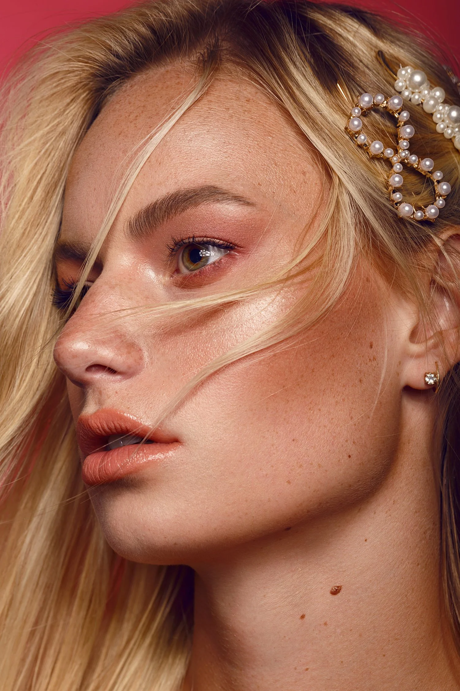 Close-up of a woman's face with blonde hair, wearing pearl and gold hairpins, small earrings, and light makeup. Beauty Photographer Los Angeles.