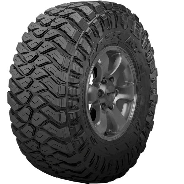 Close-up of a large, off-road tire with deep treads mounted on a silver alloy wheel.